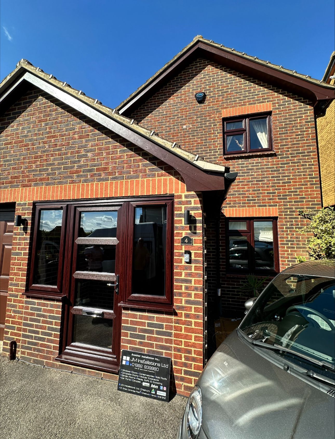 Brick house with brown windows and door; car parked in front.