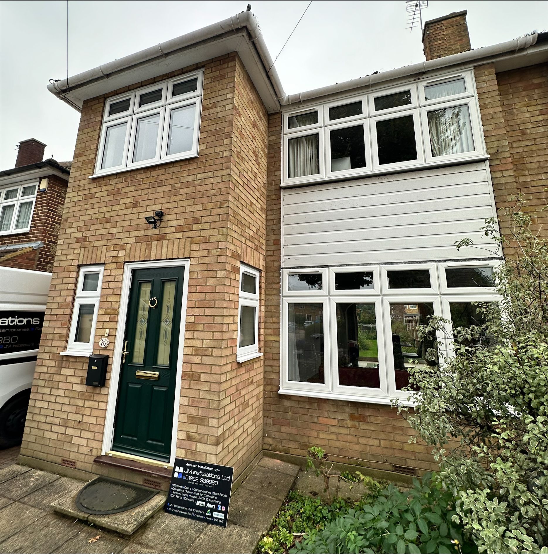 Two-story brick house with white-framed windows and a green front door.