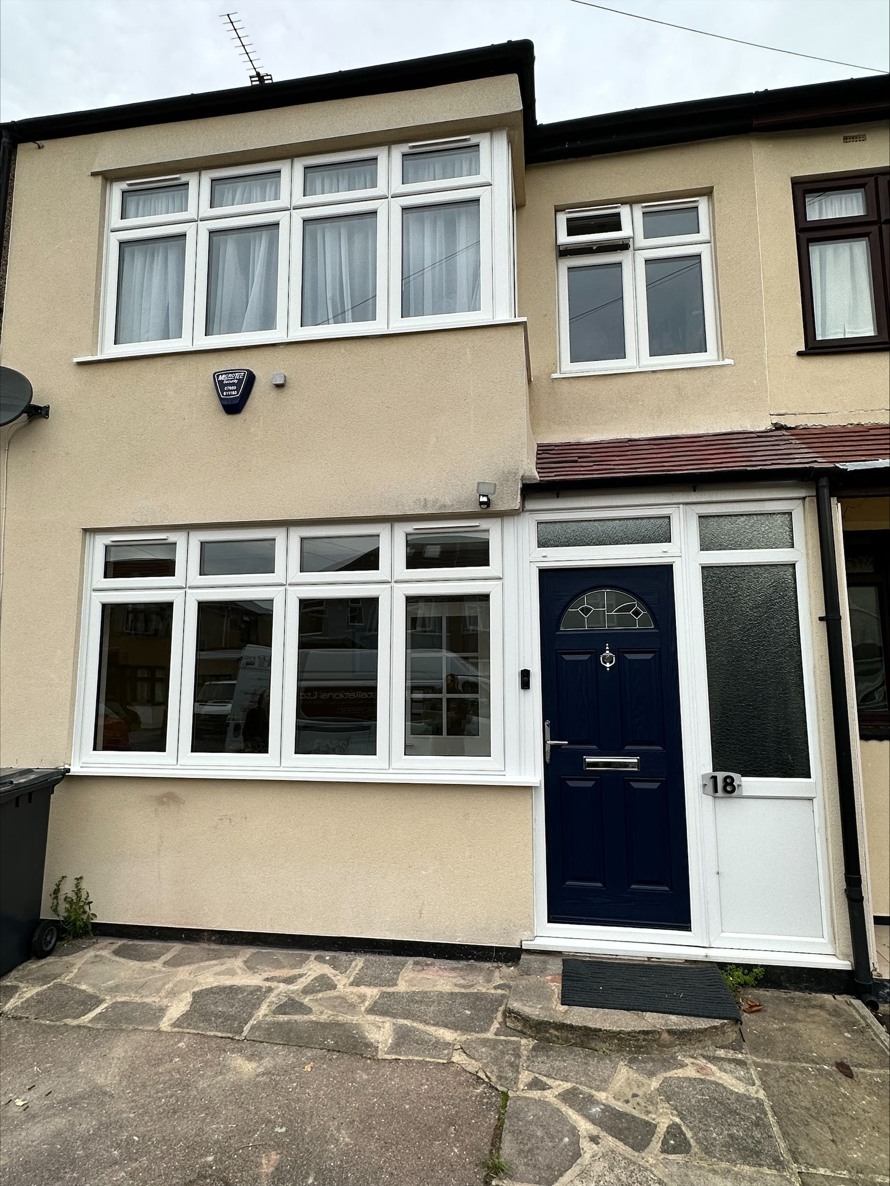 Beige terraced house with white windows and a blue door. Stone steps lead to the entrance.