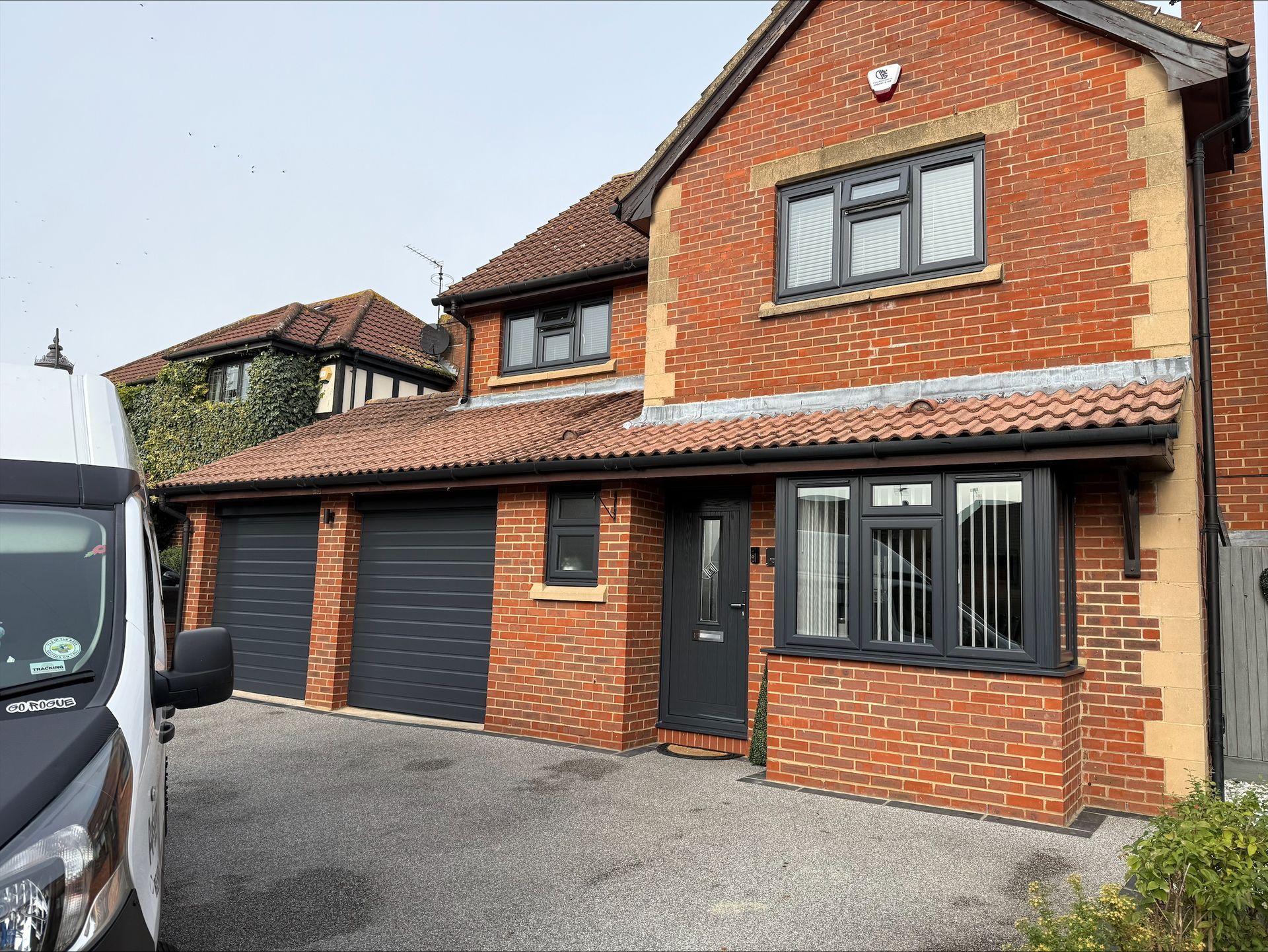 Red brick house with grey garage doors and trim, gravel driveway.