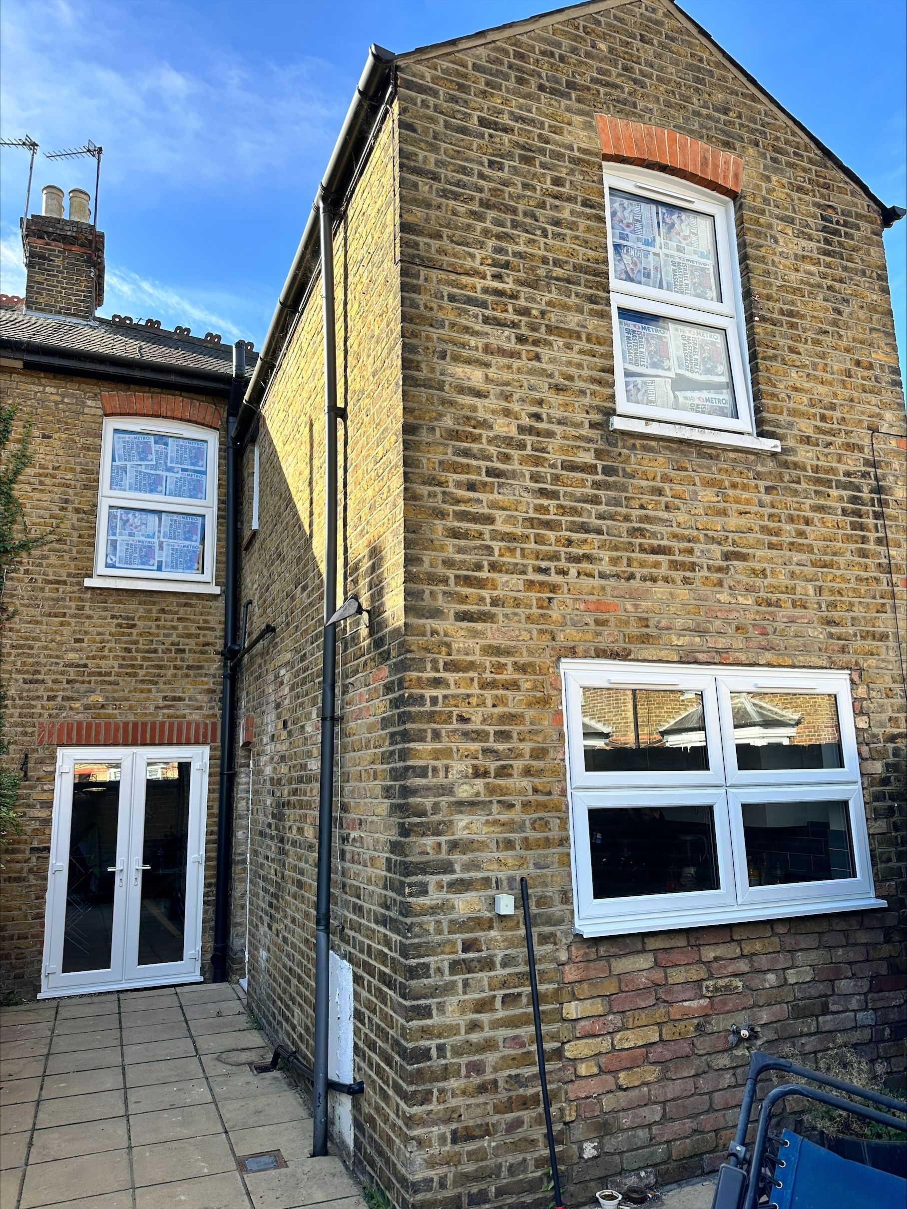 Back exterior of a brick building with white framed windows and a glass door; sunny day.
