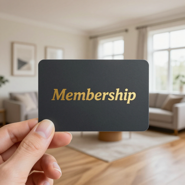 Hand holding a black membership card in a bright living room
