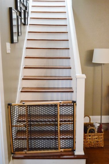 Staircase with a baby gate at the bottom and a floor lamp beside it