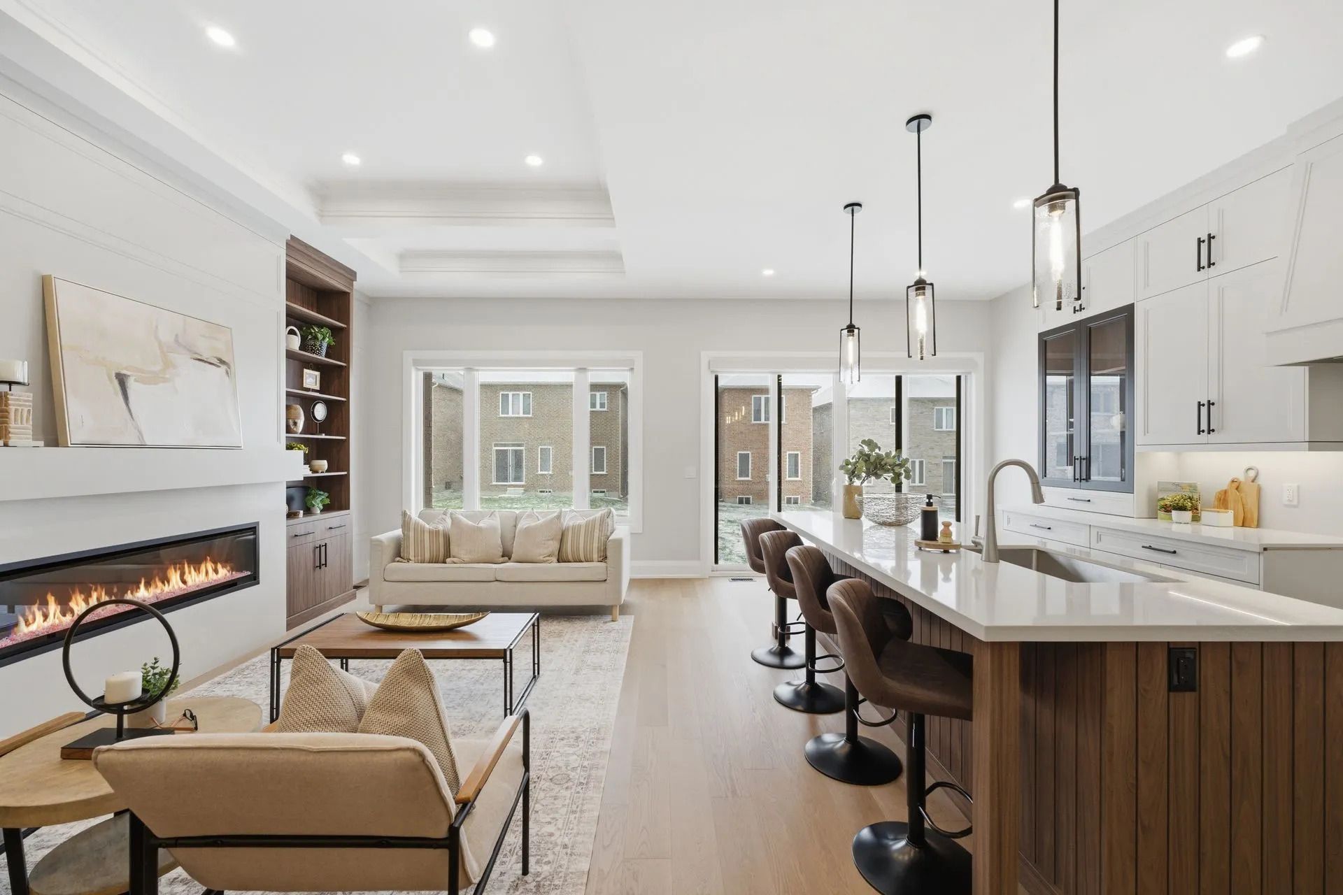Bright modern kitchen with island seating, white cabinets, and a fireplace in an open living area