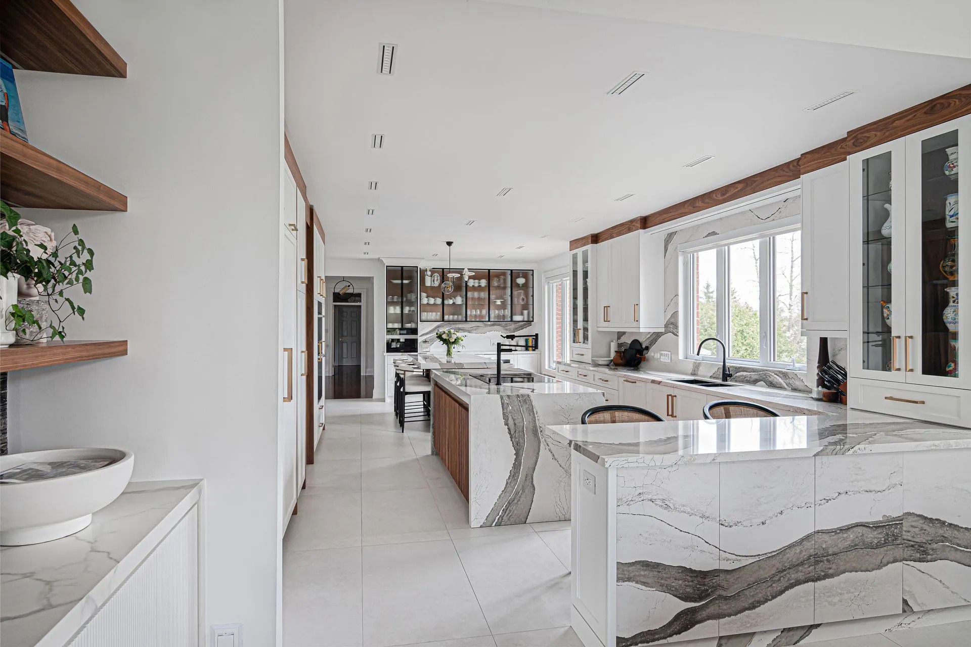 Bright modern kitchen with white marble island, built-in cabinets, and large windows