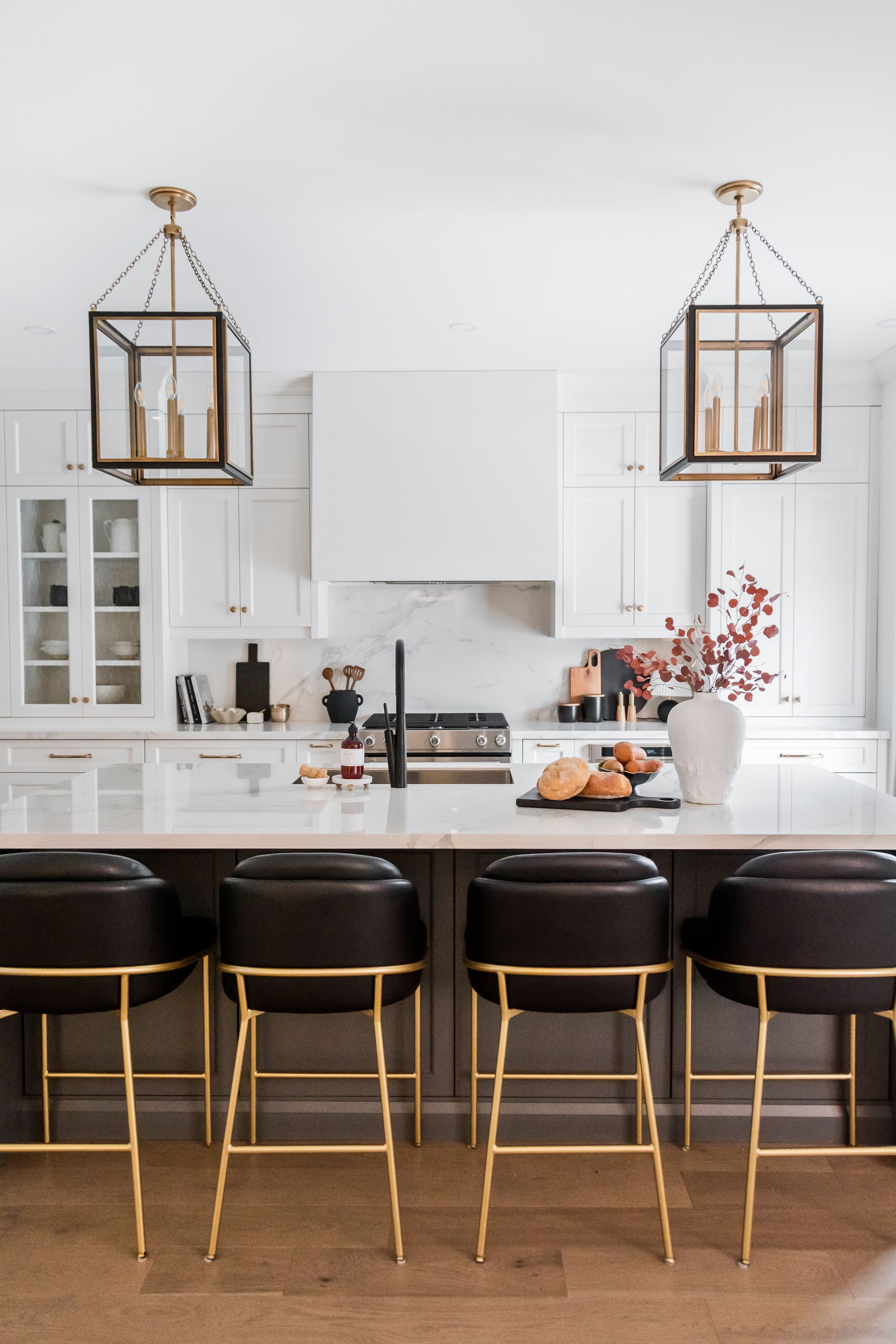 A kitchen with white cabinets and black bar stools