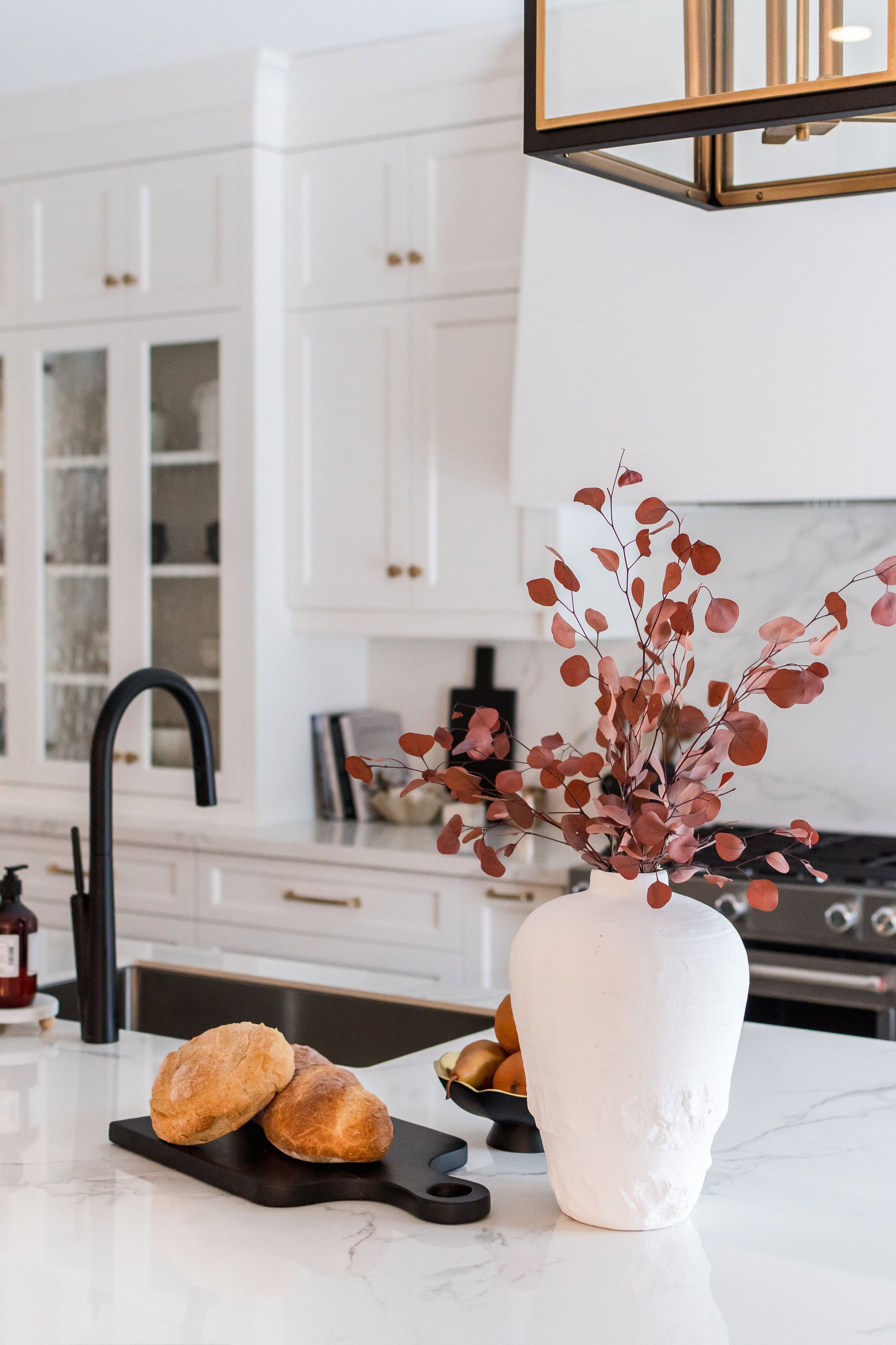 A kitchen counter with a vase of flowers and bread on it.
