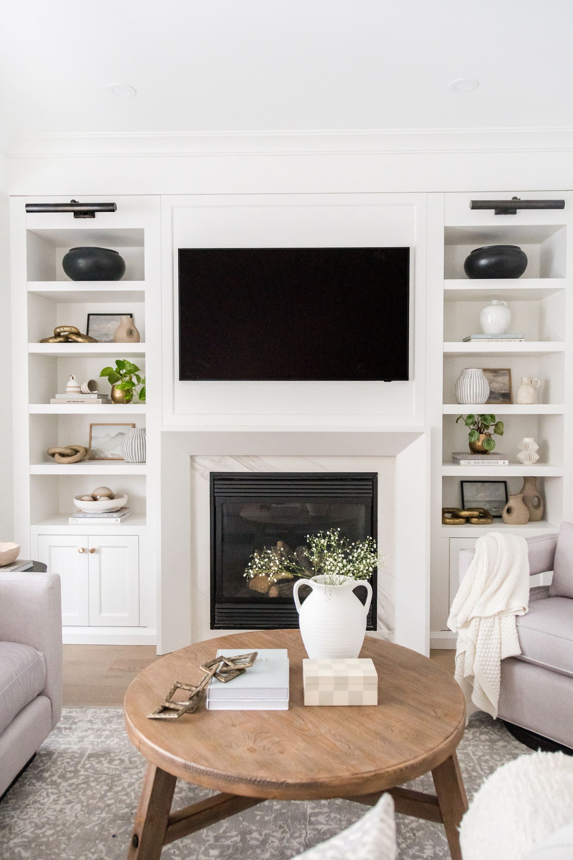 A living room with a fireplace and a flat screen tv on the wall.