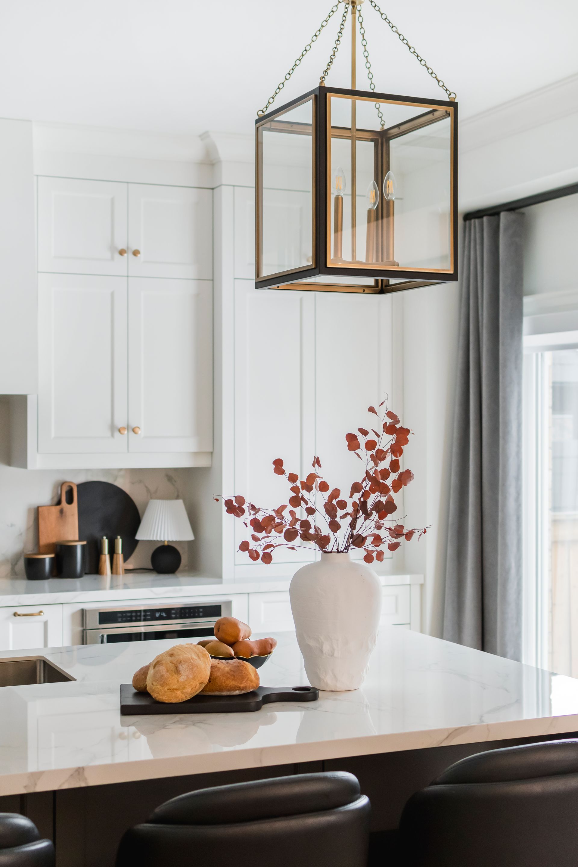 A kitchen with a lantern hanging from the ceiling and a vase of flowers on the counter.