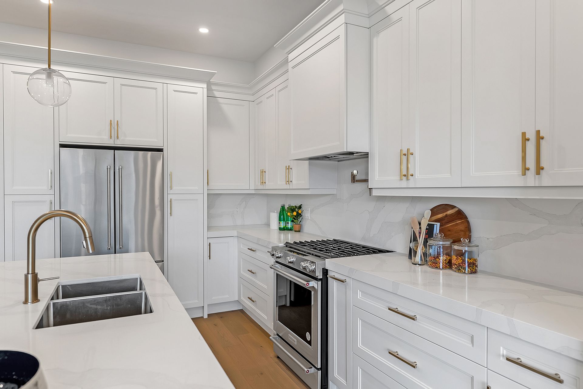 A kitchen with white cabinets , stainless steel appliances , a sink , and a refrigerator.