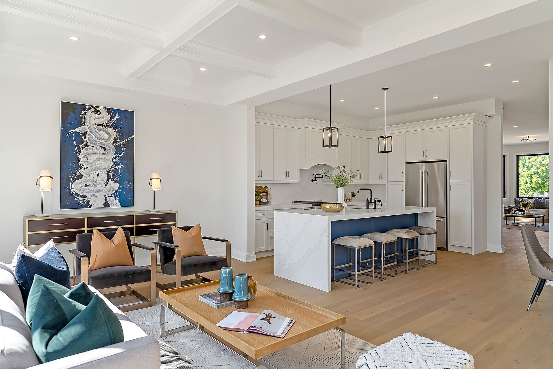 A living room with a couch , chairs , a coffee table and a kitchen.