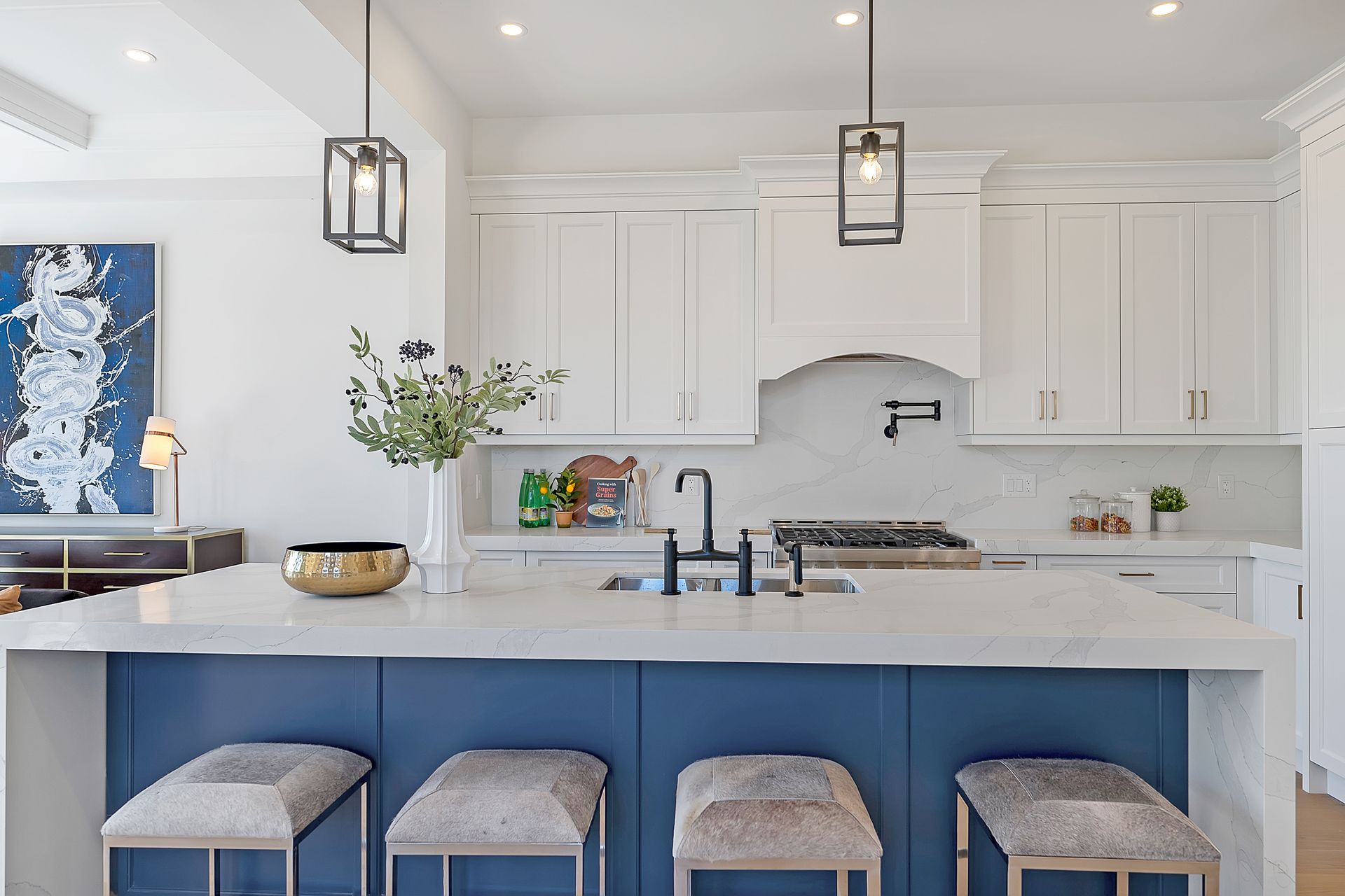 A kitchen with white cabinets and a blue island with stools