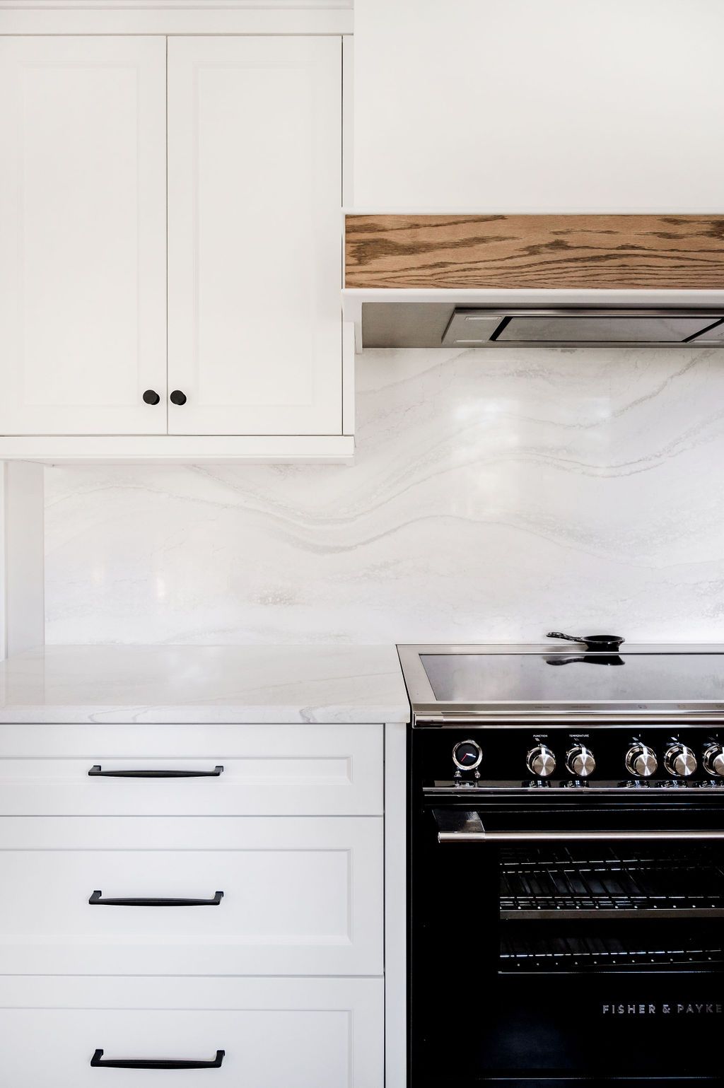 A kitchen with white cabinets and a black stove top oven