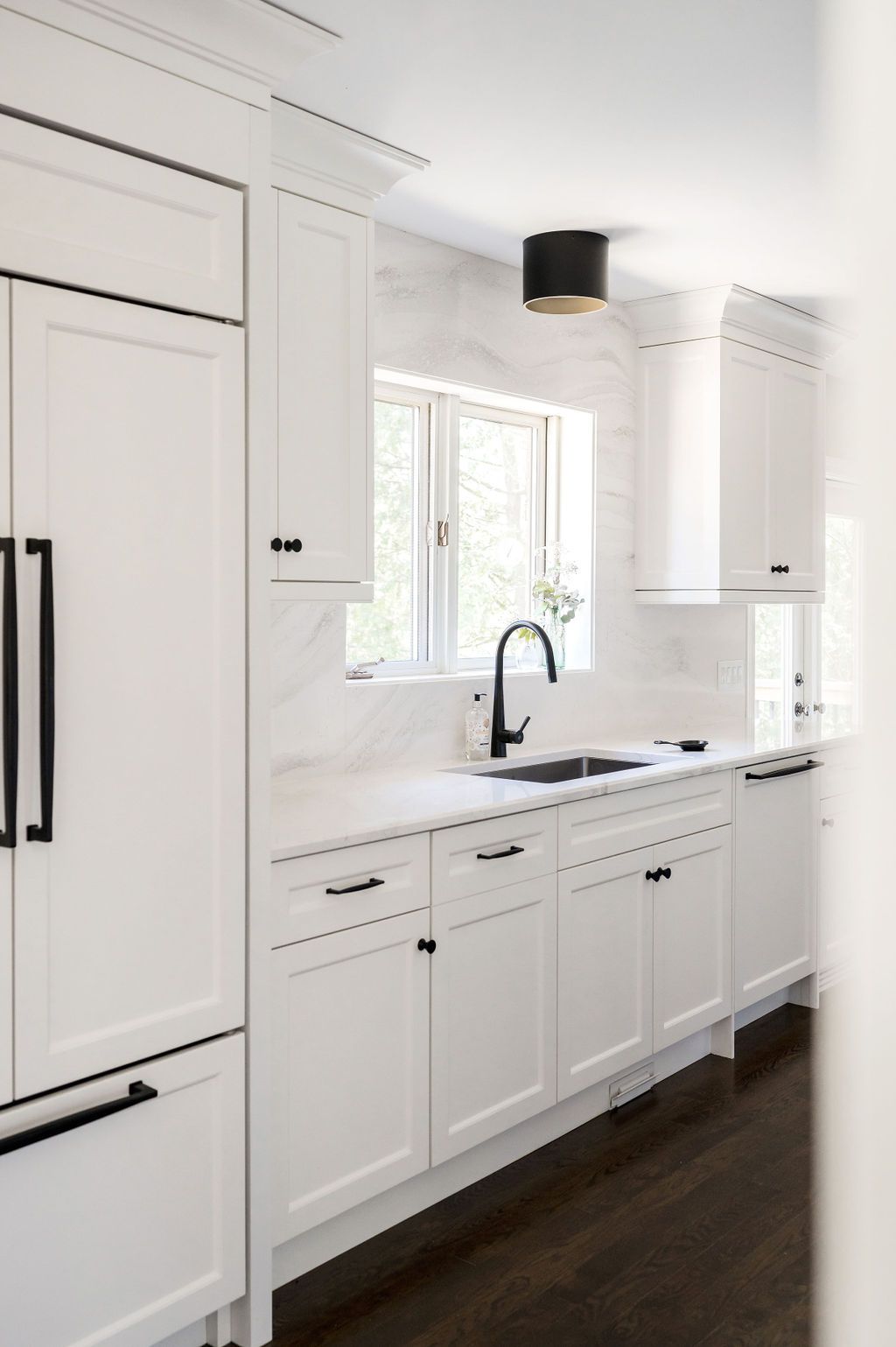 A kitchen with white cabinets and black handles