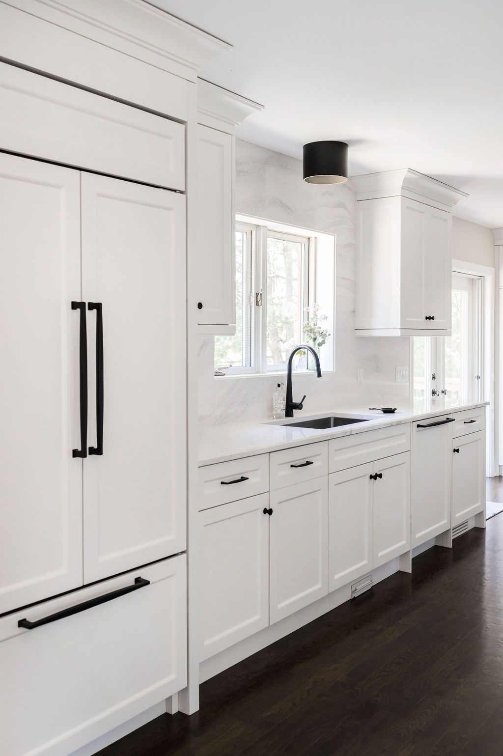 A kitchen with white cabinets and black handles