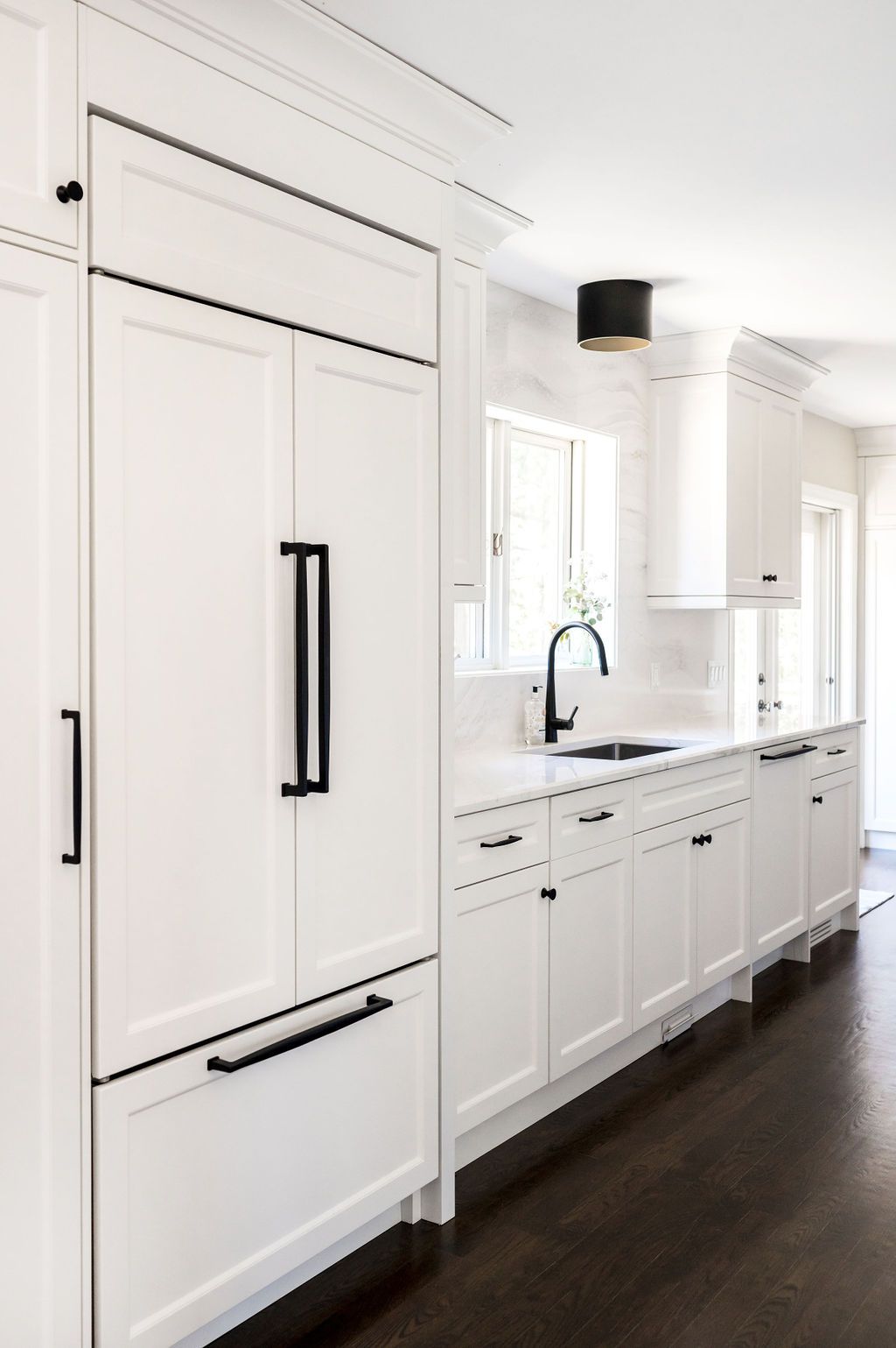 A kitchen with white cabinets and black handles