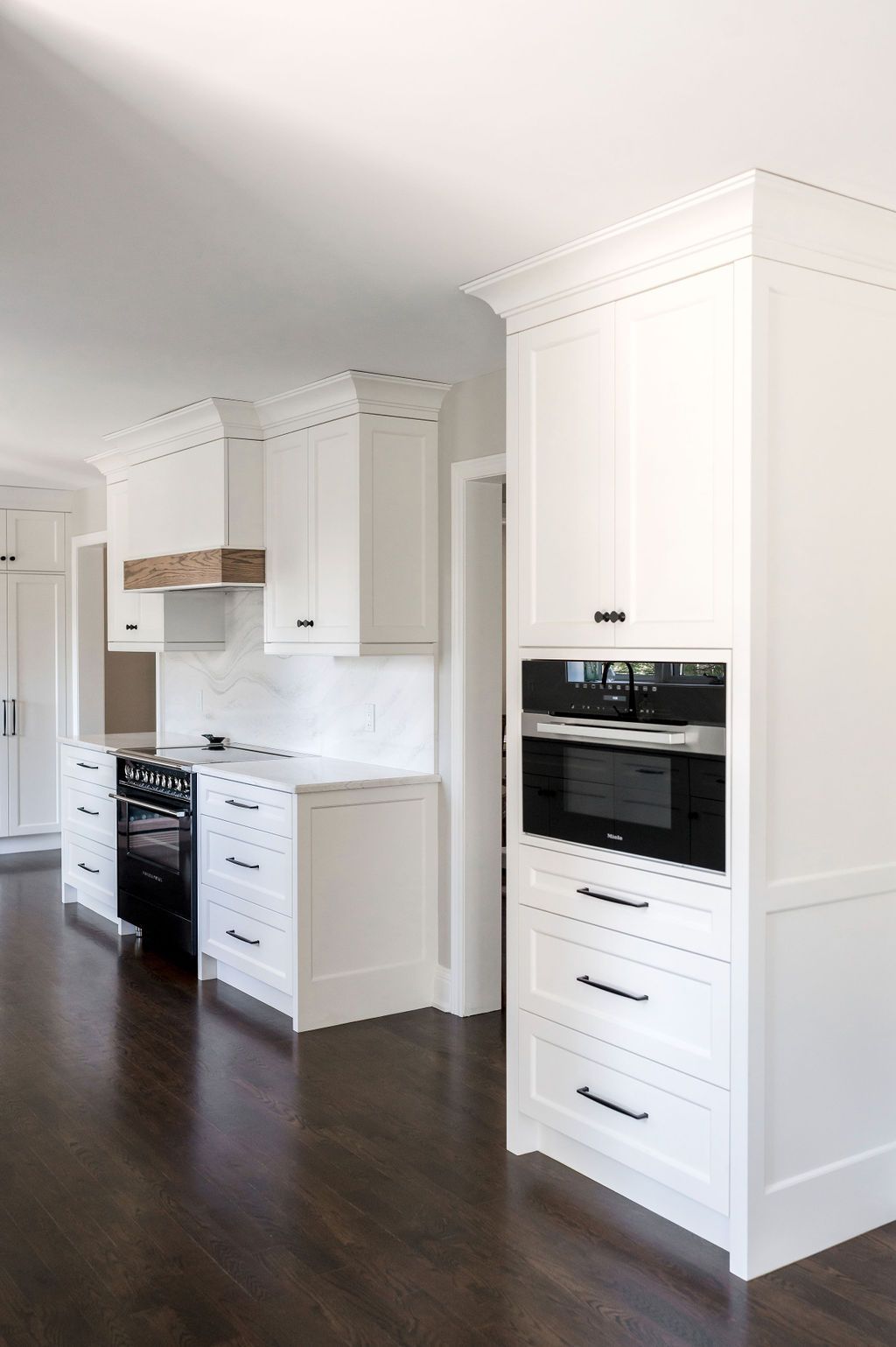 A kitchen with white cabinets , a stove , and a microwave.