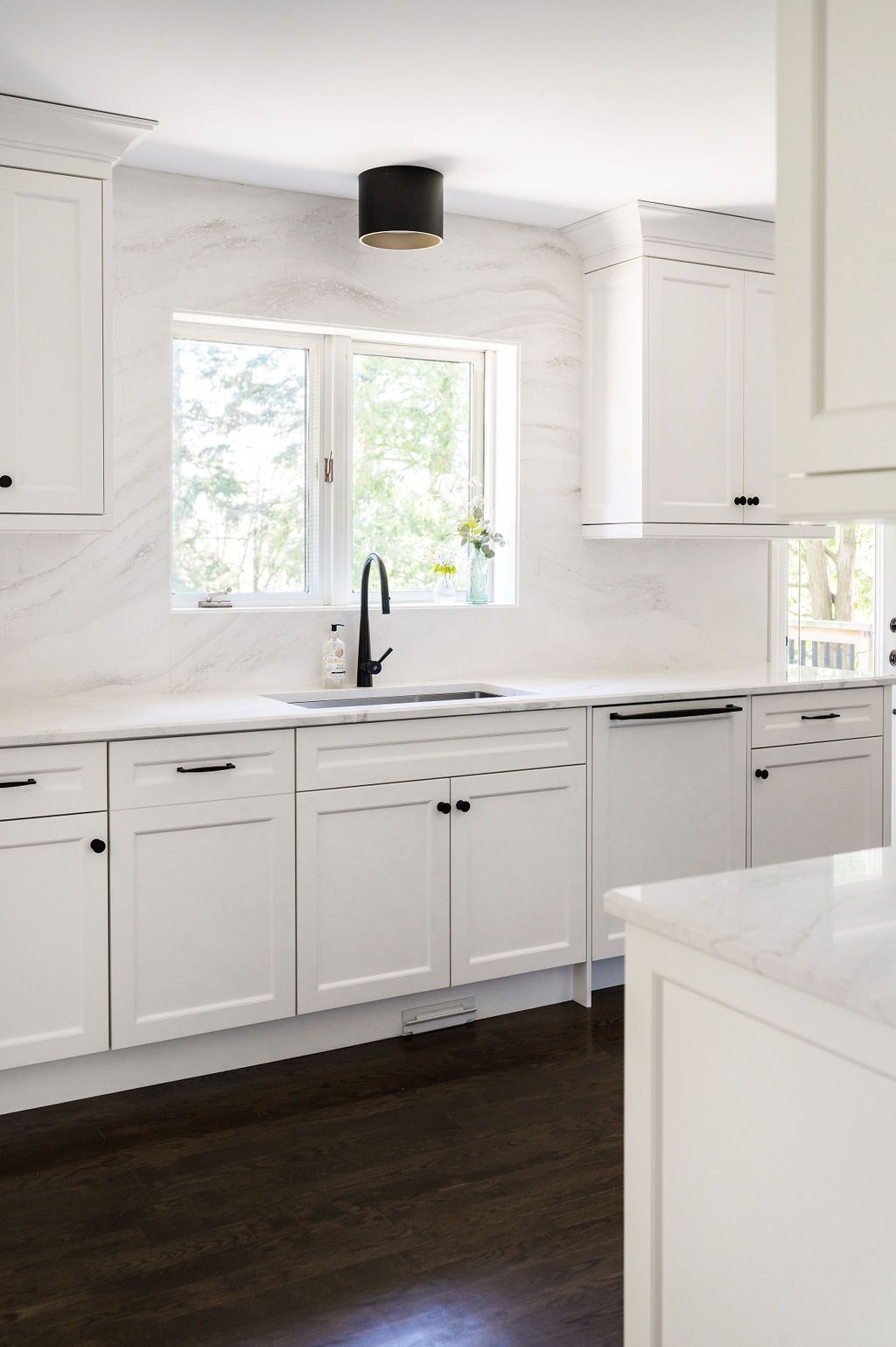 A kitchen with white cabinets a sink and a window