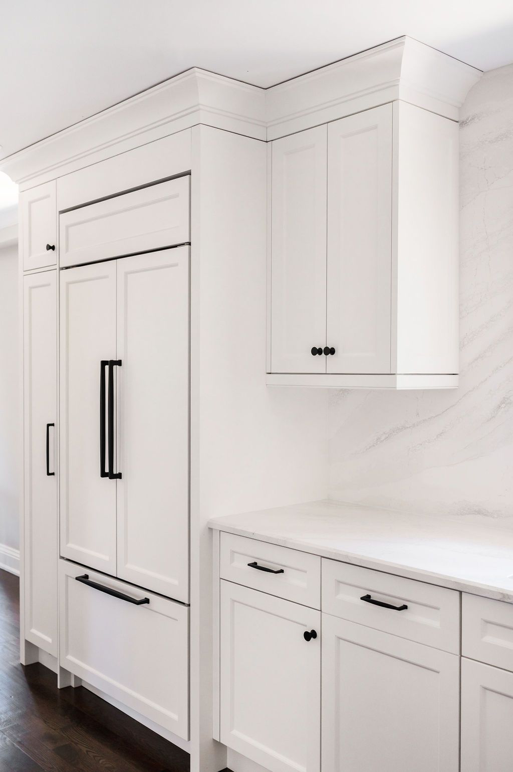 A kitchen with white cabinets and black handles