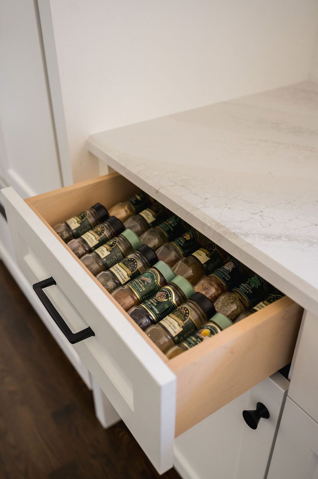 A drawer filled with bottles of spices in a kitchen.