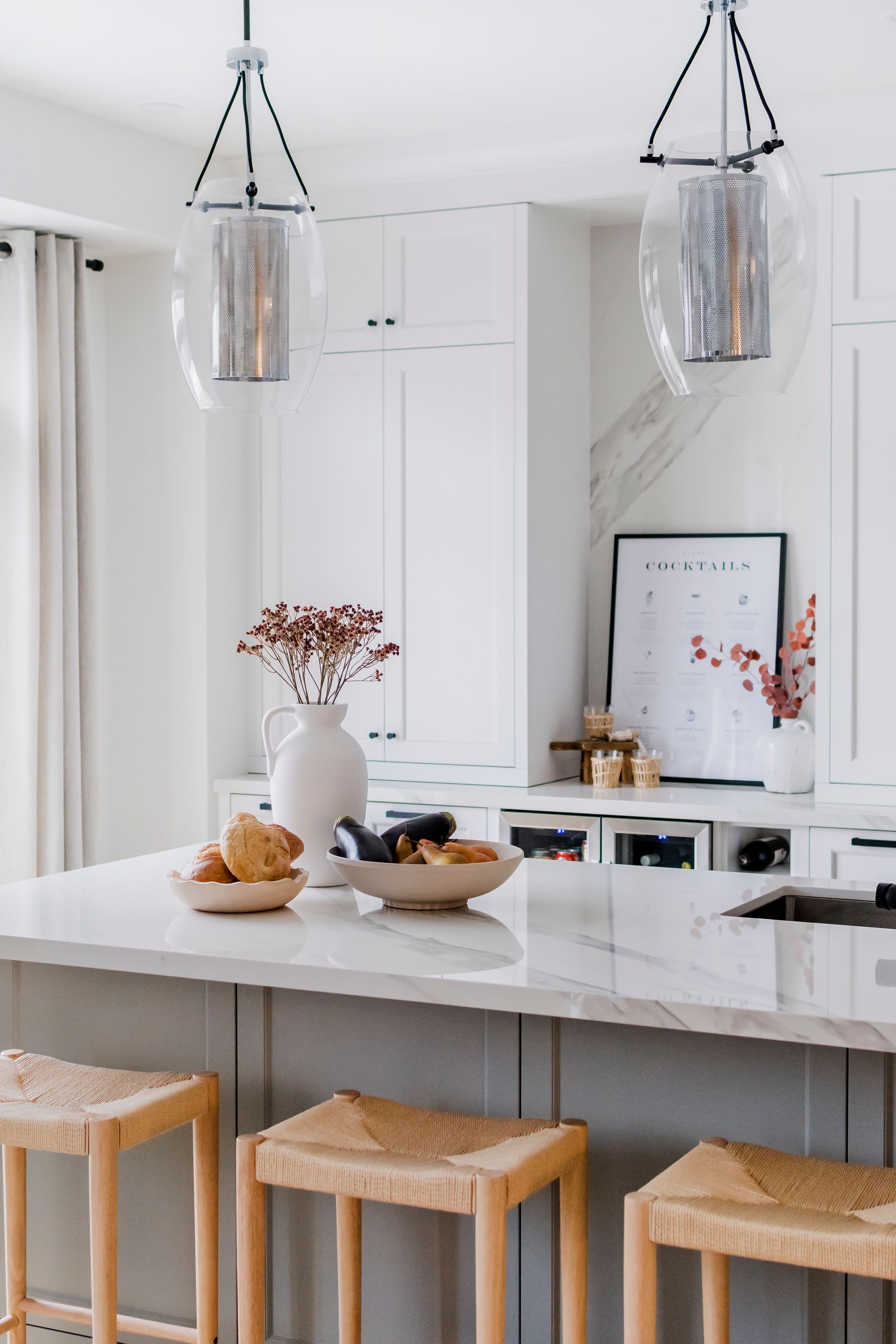 A kitchen with a large island and wicker stools.