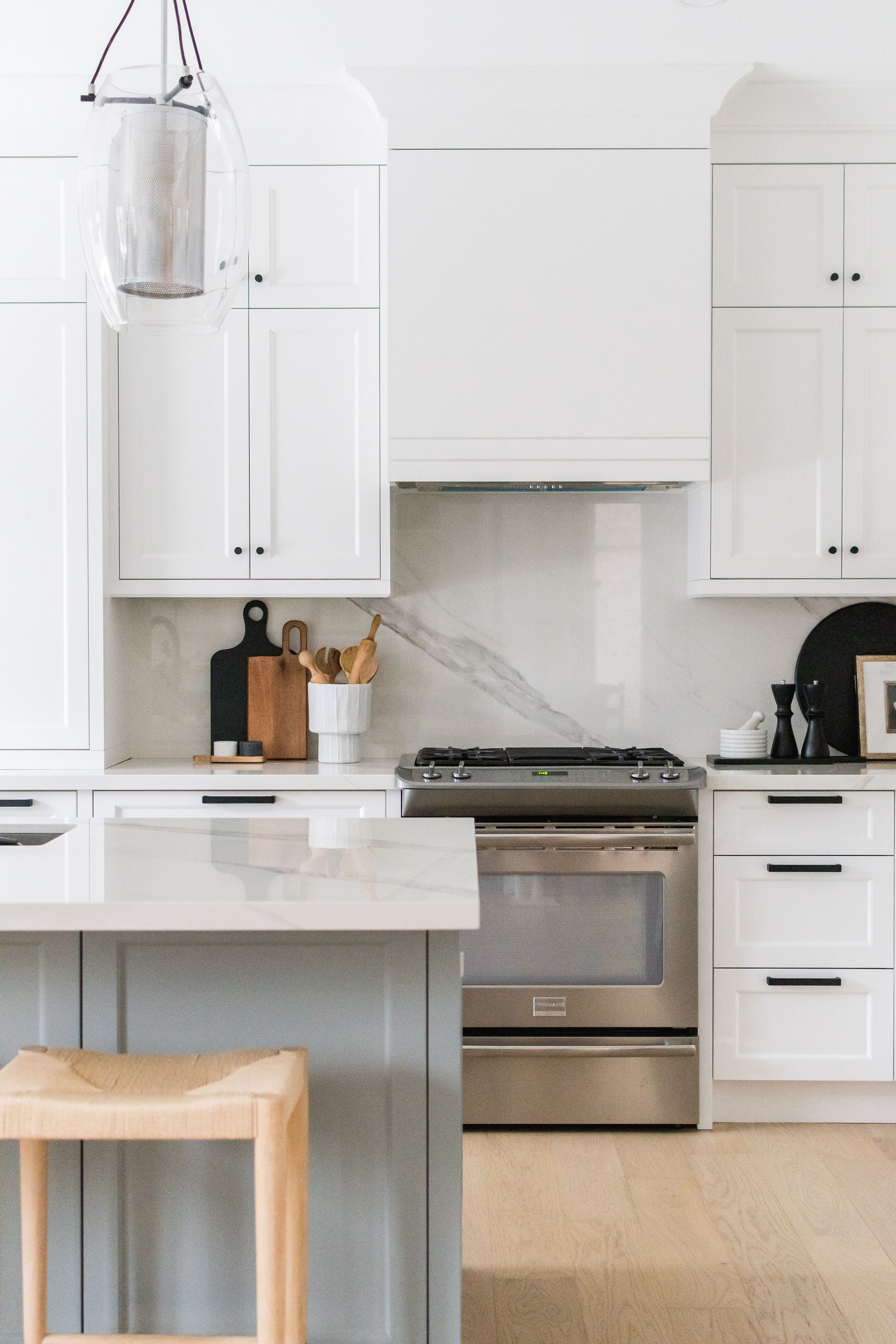 A kitchen with white cabinets , stainless steel appliances , and a large island.