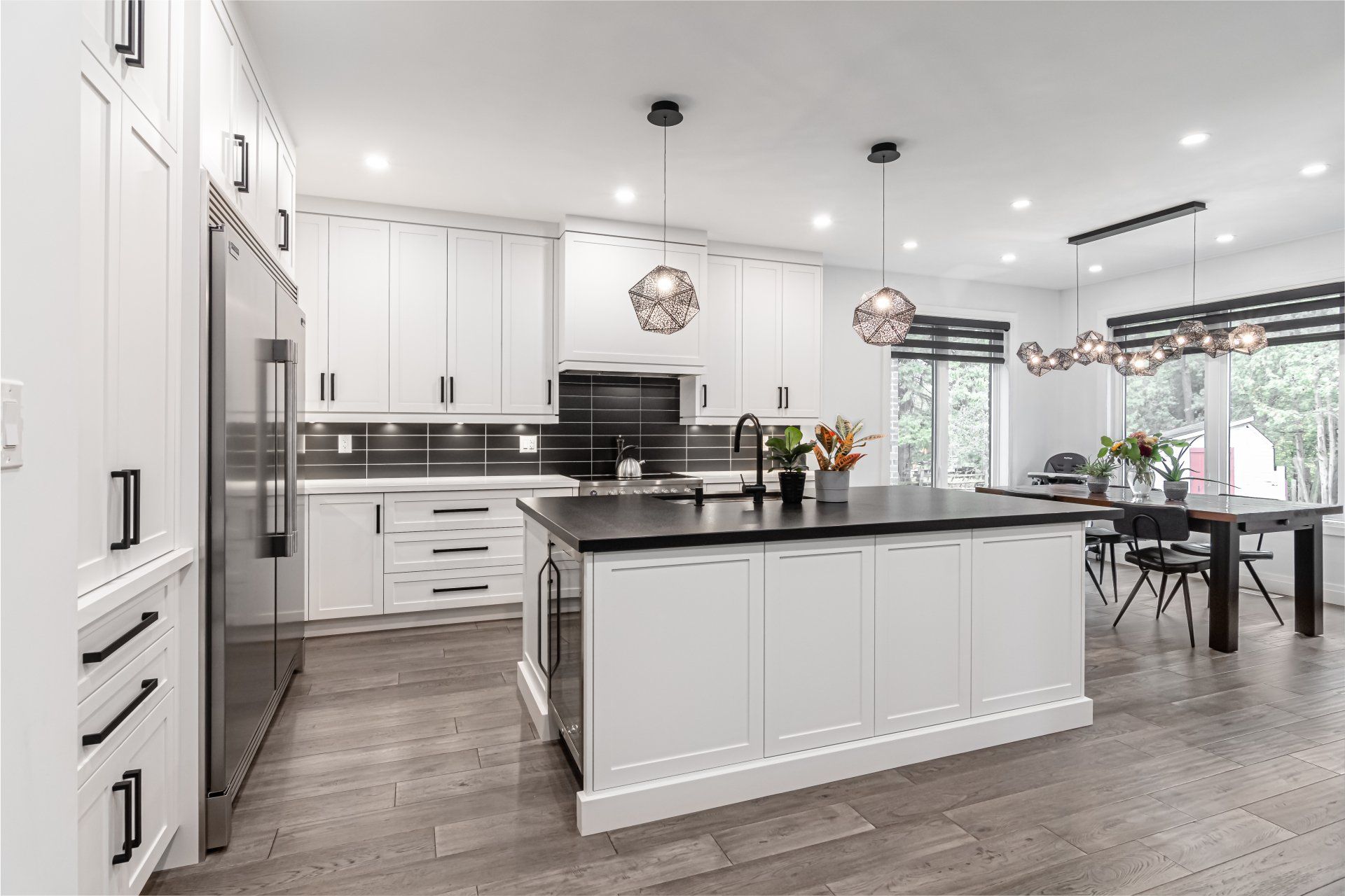 A kitchen with white cabinets and stainless steel appliances and a large island in the middle.