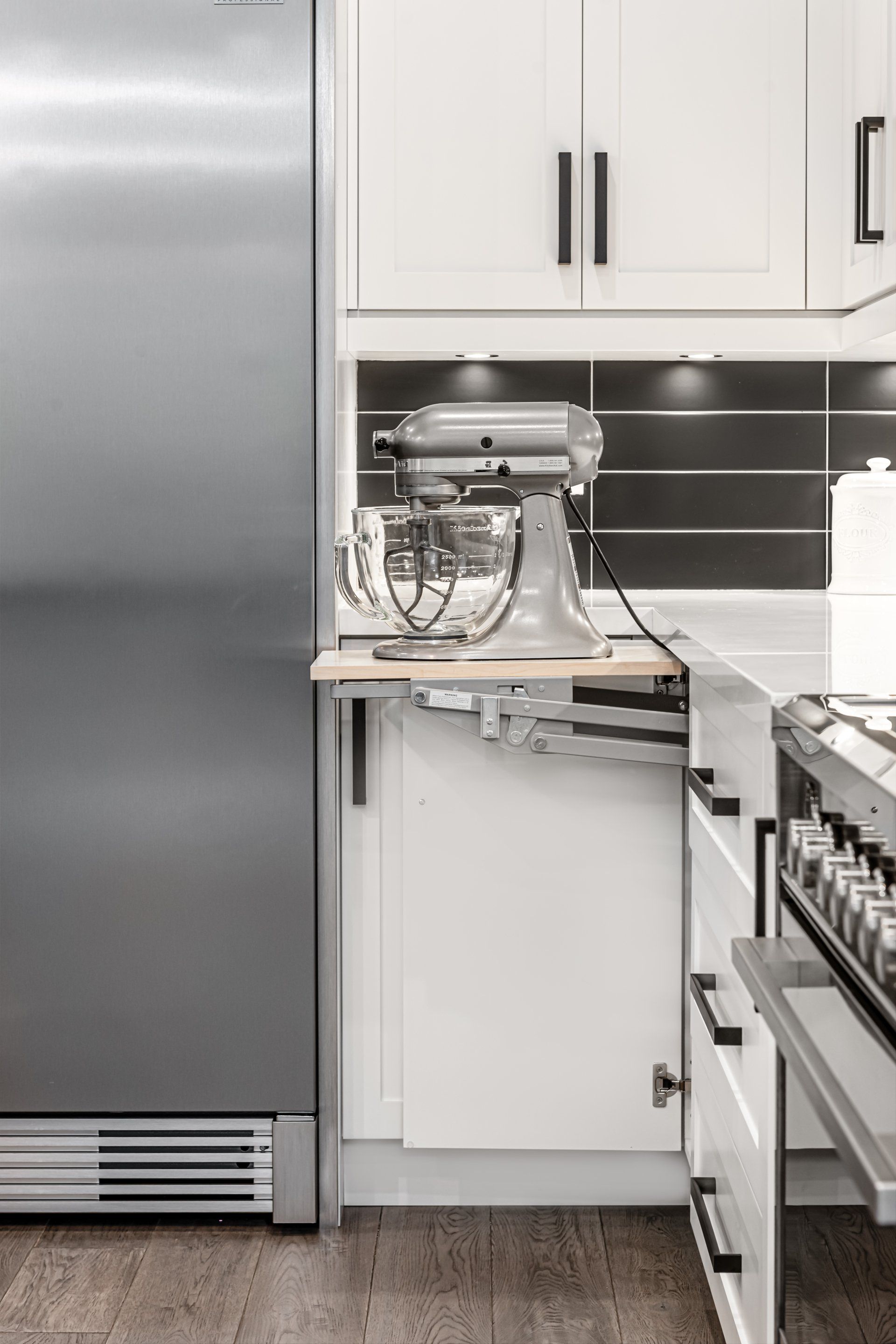 A kitchen with a stainless steel refrigerator and a mixer on the counter.