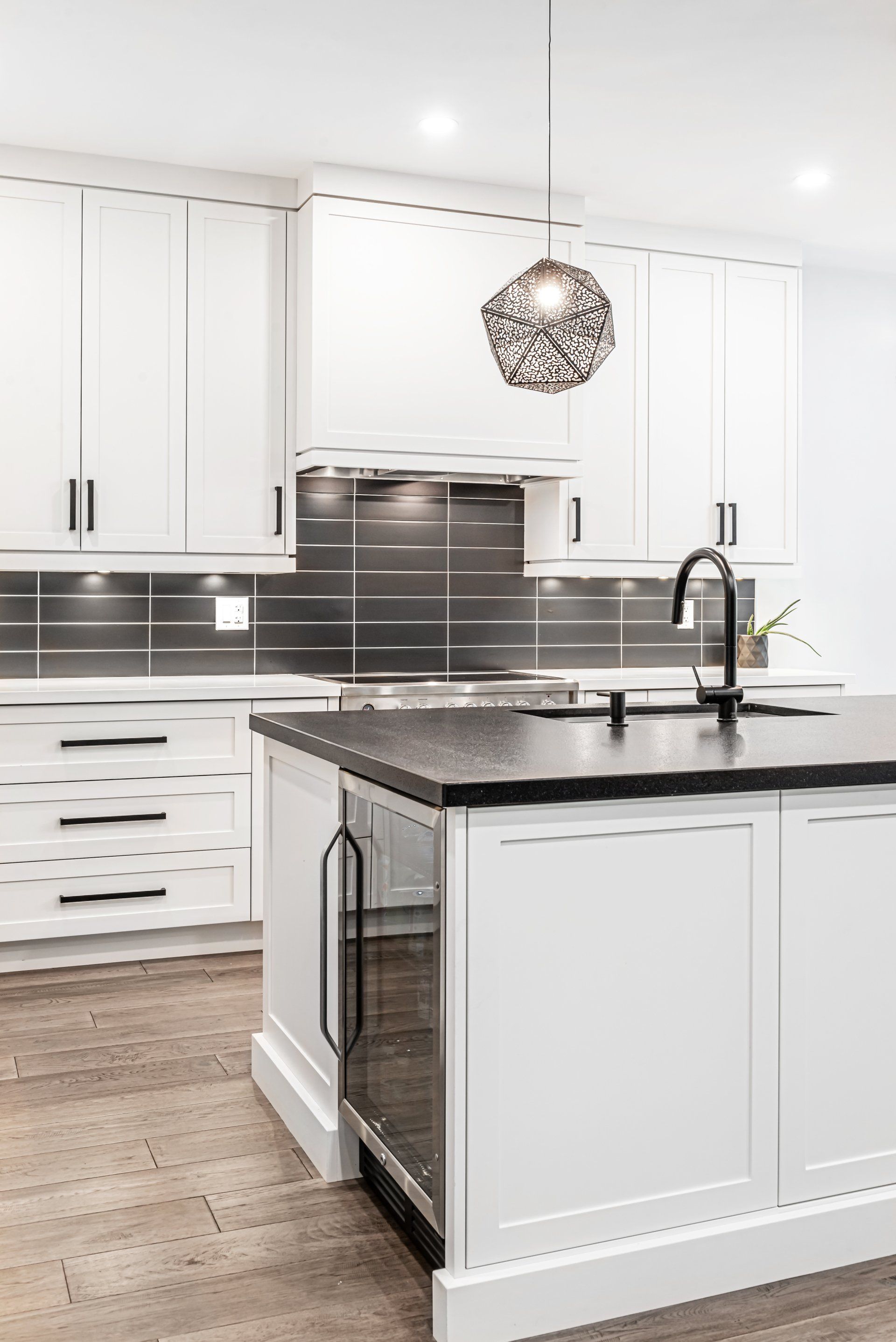 A kitchen with white cabinets , black counter tops , and a large island.