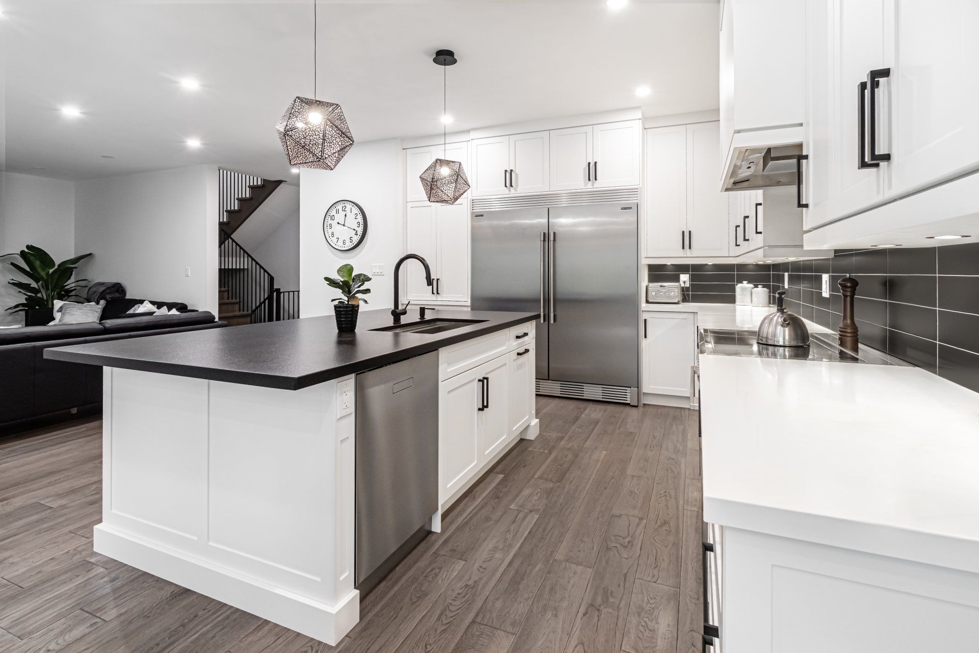 A kitchen with white cabinets and stainless steel appliances and a large island.