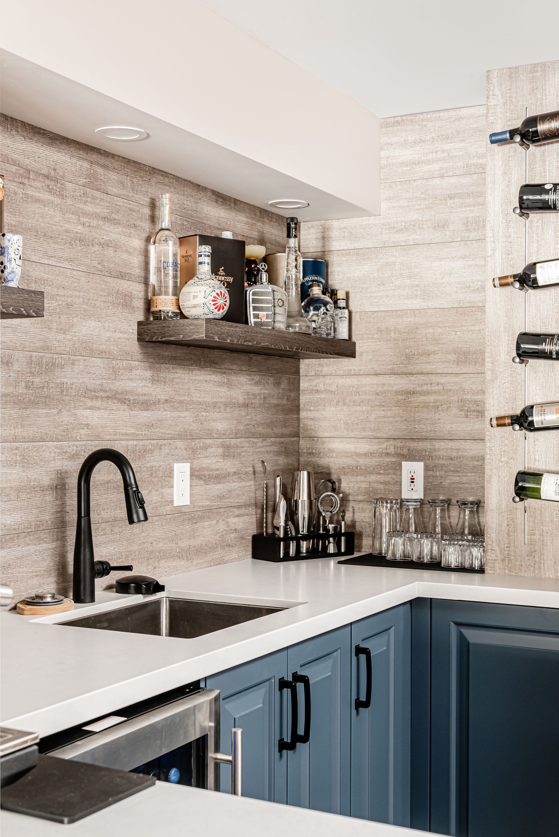 A kitchen with blue cabinets , a sink , and a wine rack.