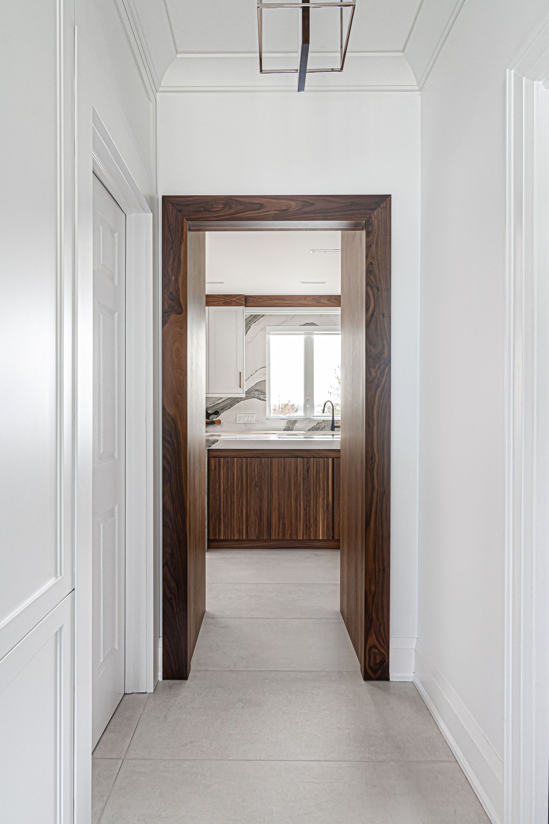 A hallway with a wooden door leading to a kitchen.