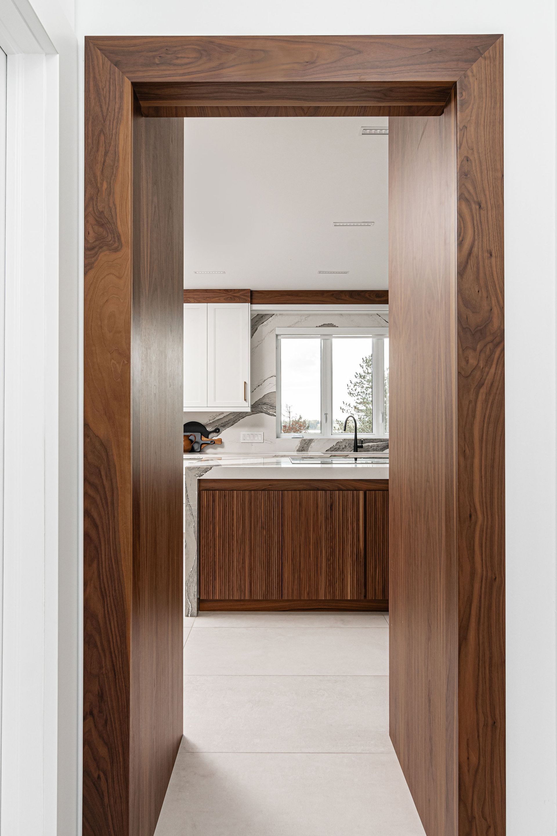 A hallway with a wooden door leading to a kitchen.