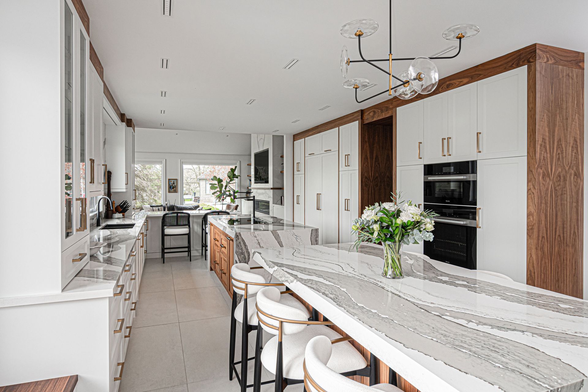 A kitchen with white cabinets , granite counter tops , stools and a large island.