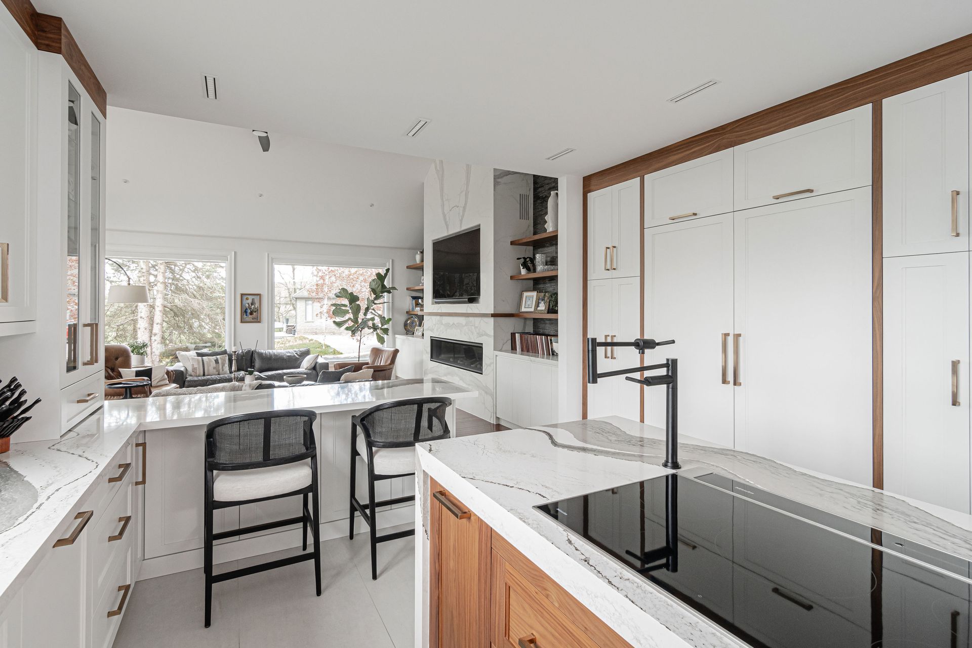A kitchen with white cabinets and wooden cabinets and a large island with a stove top oven.