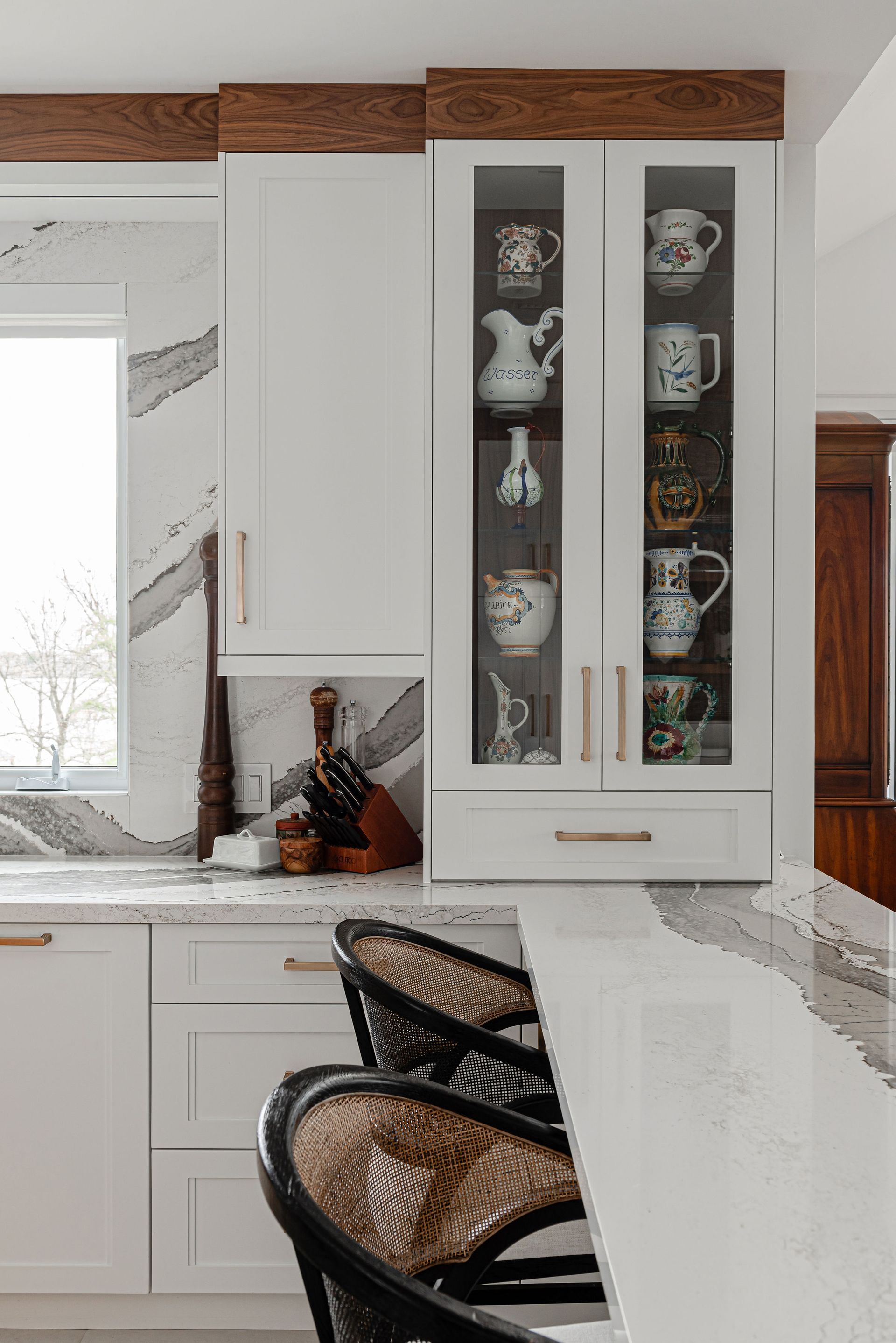 A kitchen with white cabinets , a sink , a counter and a window.