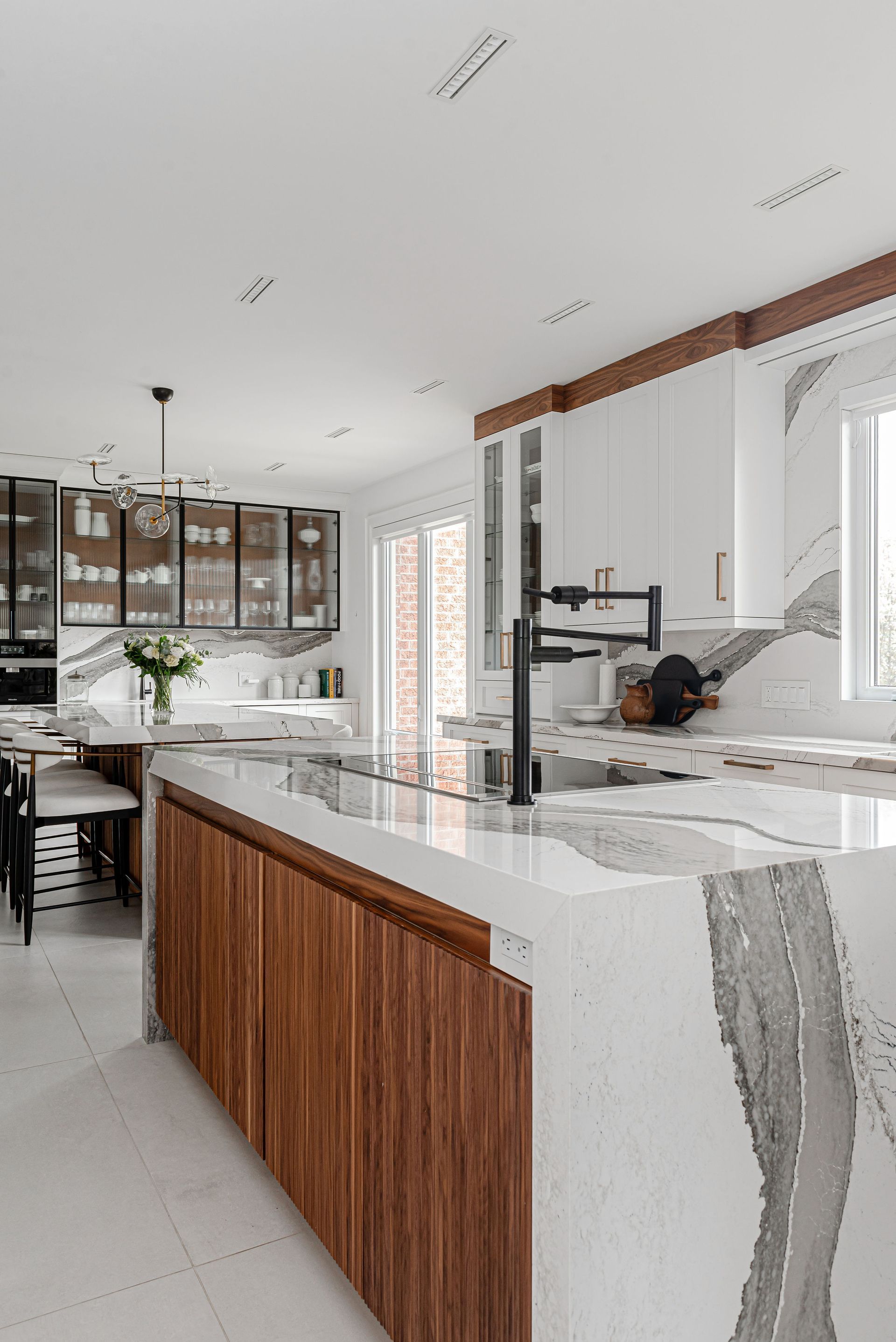 A kitchen with white cabinets , marble counter tops , and wooden cabinets.