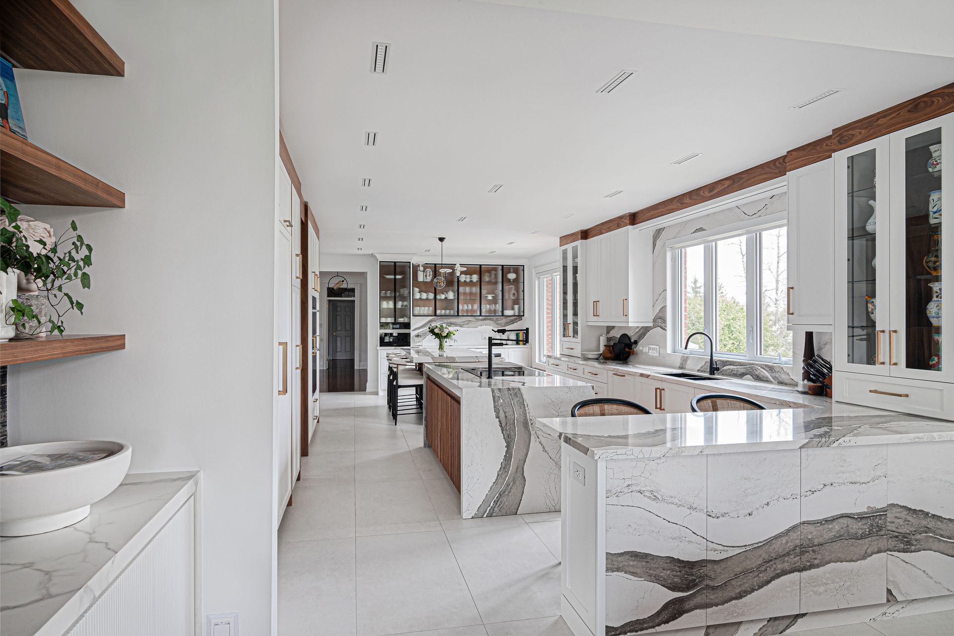 A large kitchen with white cabinets and marble counter tops.