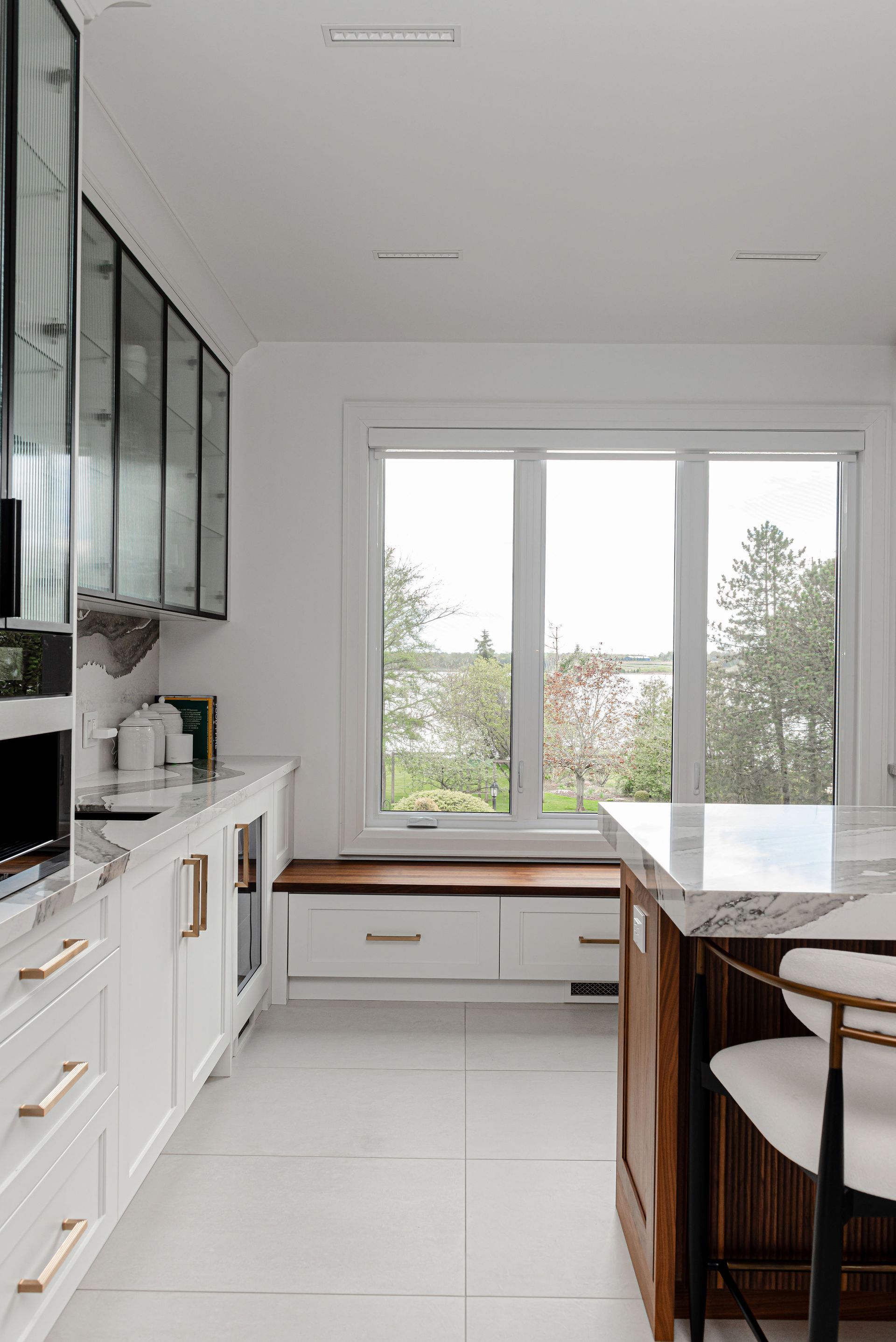 A kitchen with white cabinets and a large window.