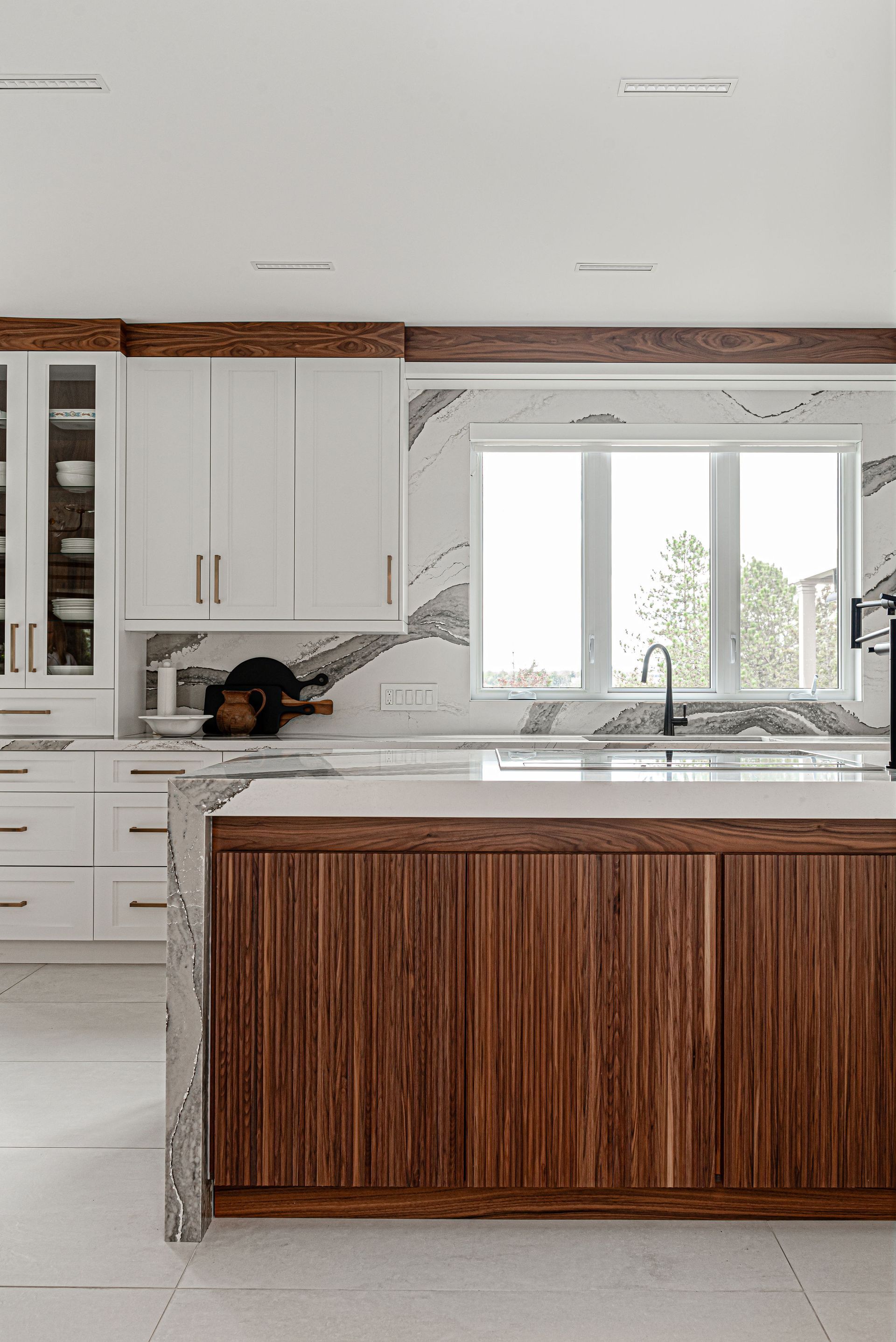 A kitchen with white cabinets and wooden cabinets and a large island.