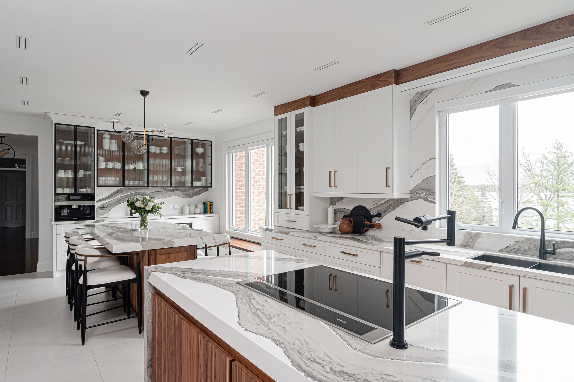 A kitchen with white cabinets , a large island , a sink , and a stove.