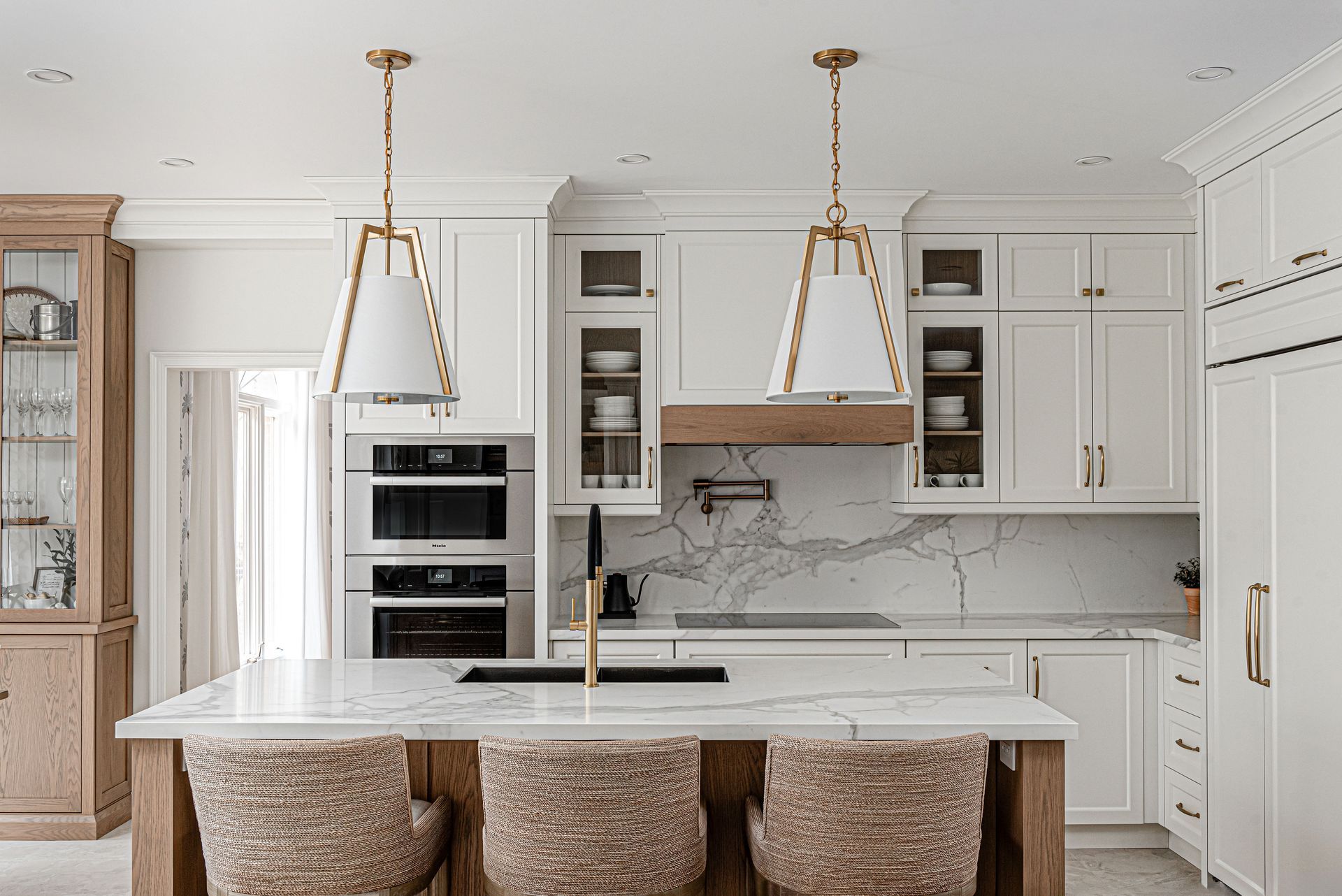 A kitchen with white cabinets , marble counter tops , stainless steel appliances , and a large island.