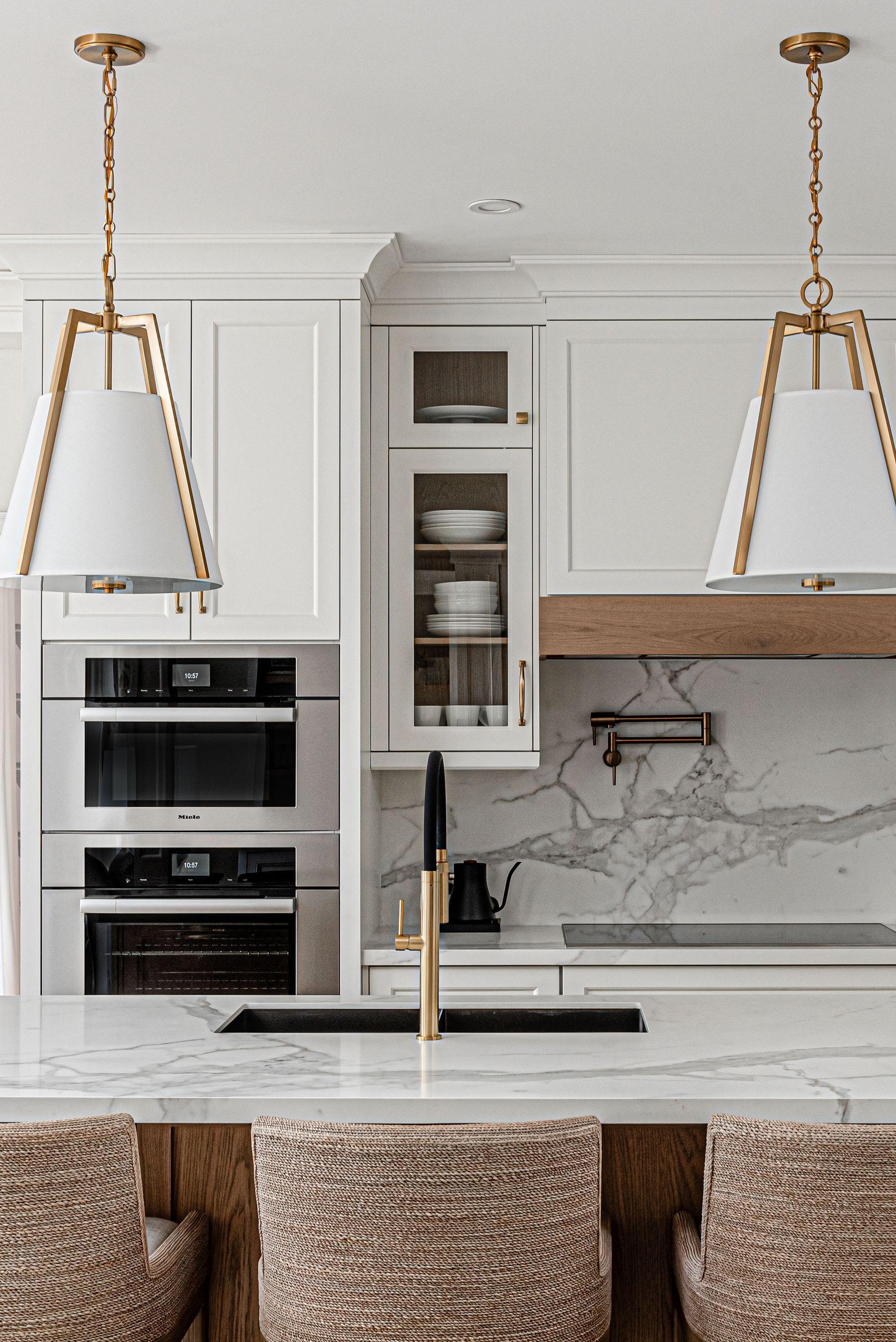 A kitchen with white cabinets , stainless steel appliances , a sink , and a marble counter top.