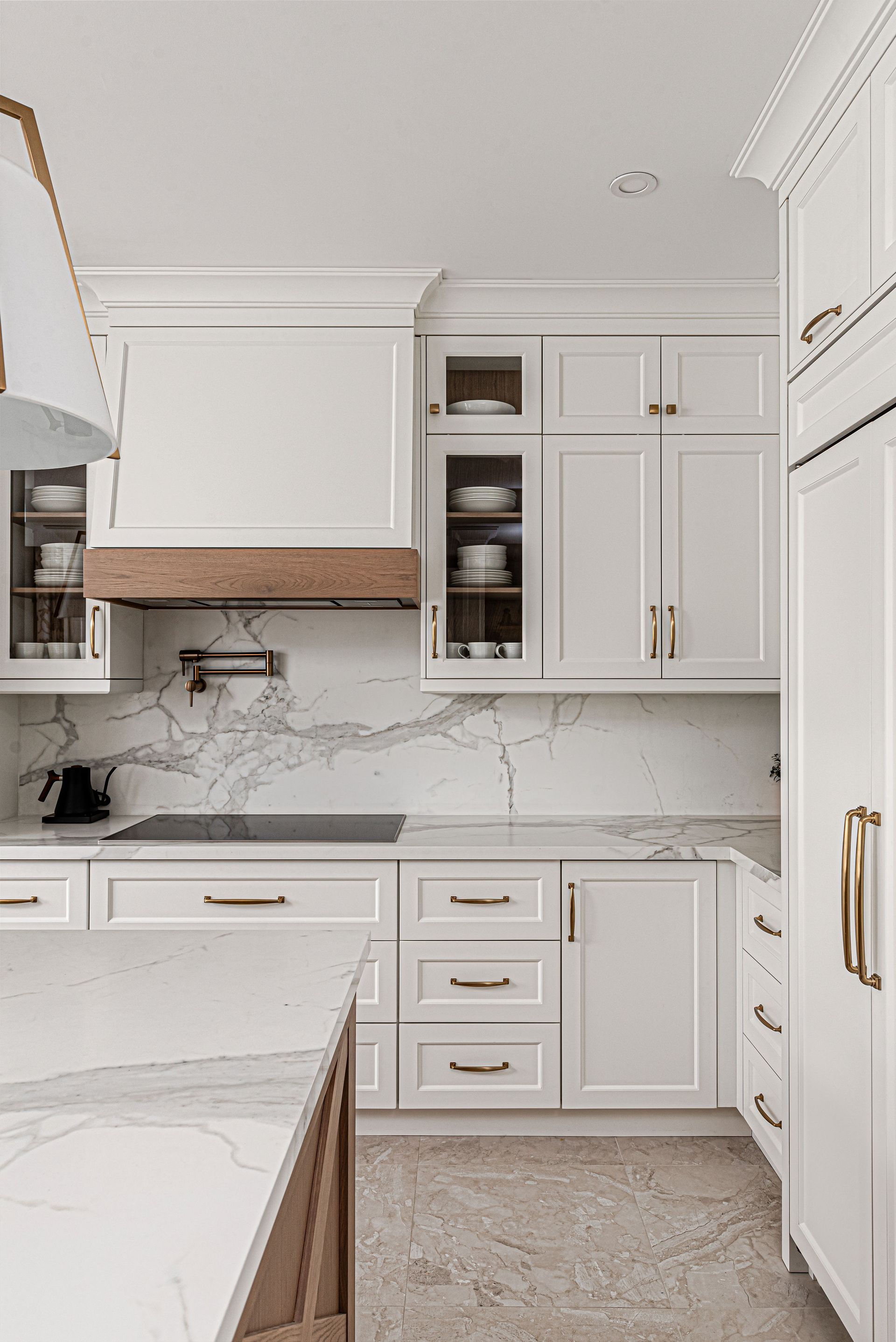 A kitchen with white cabinets and marble counter tops.