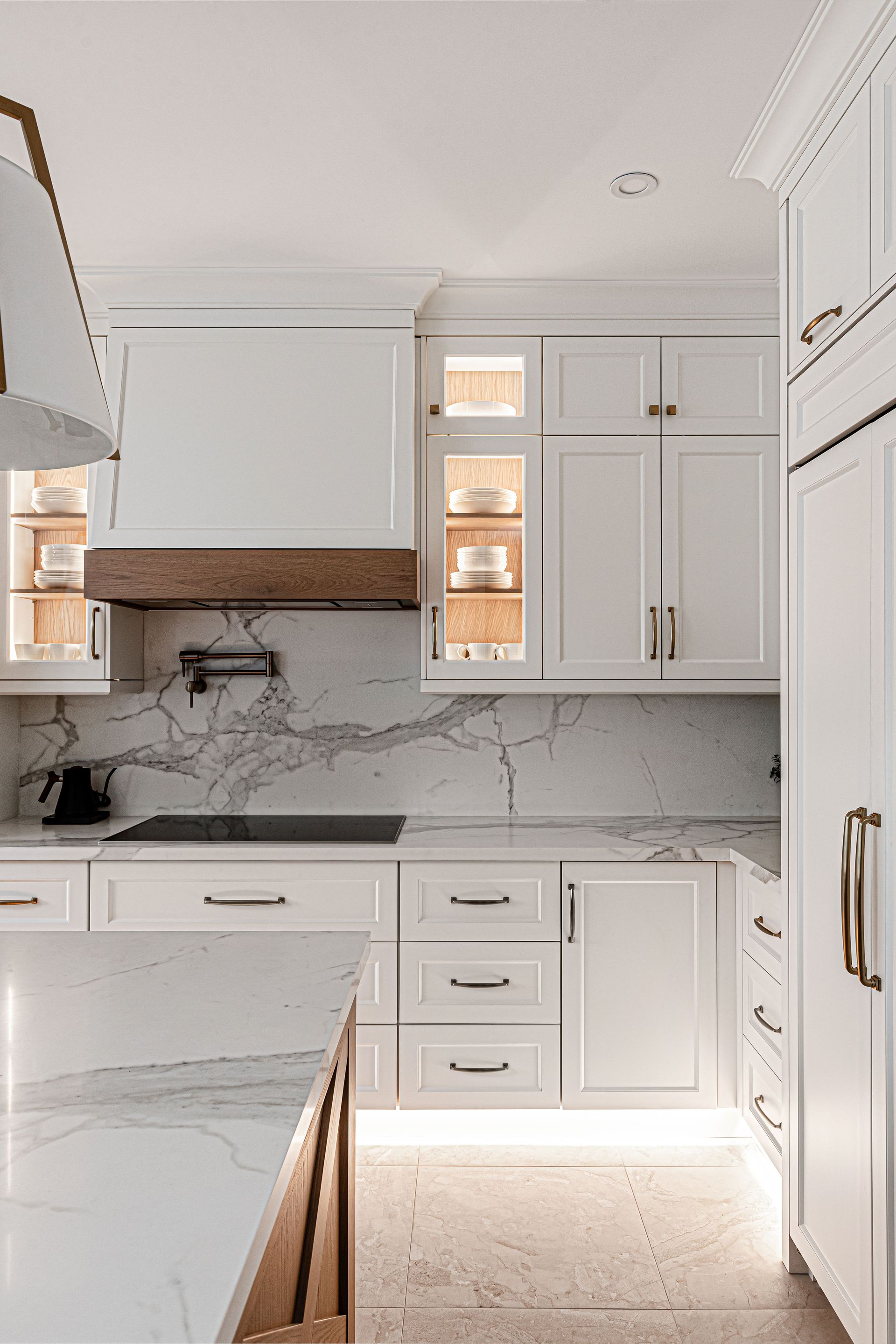 A kitchen with white cabinets and marble counter tops.
