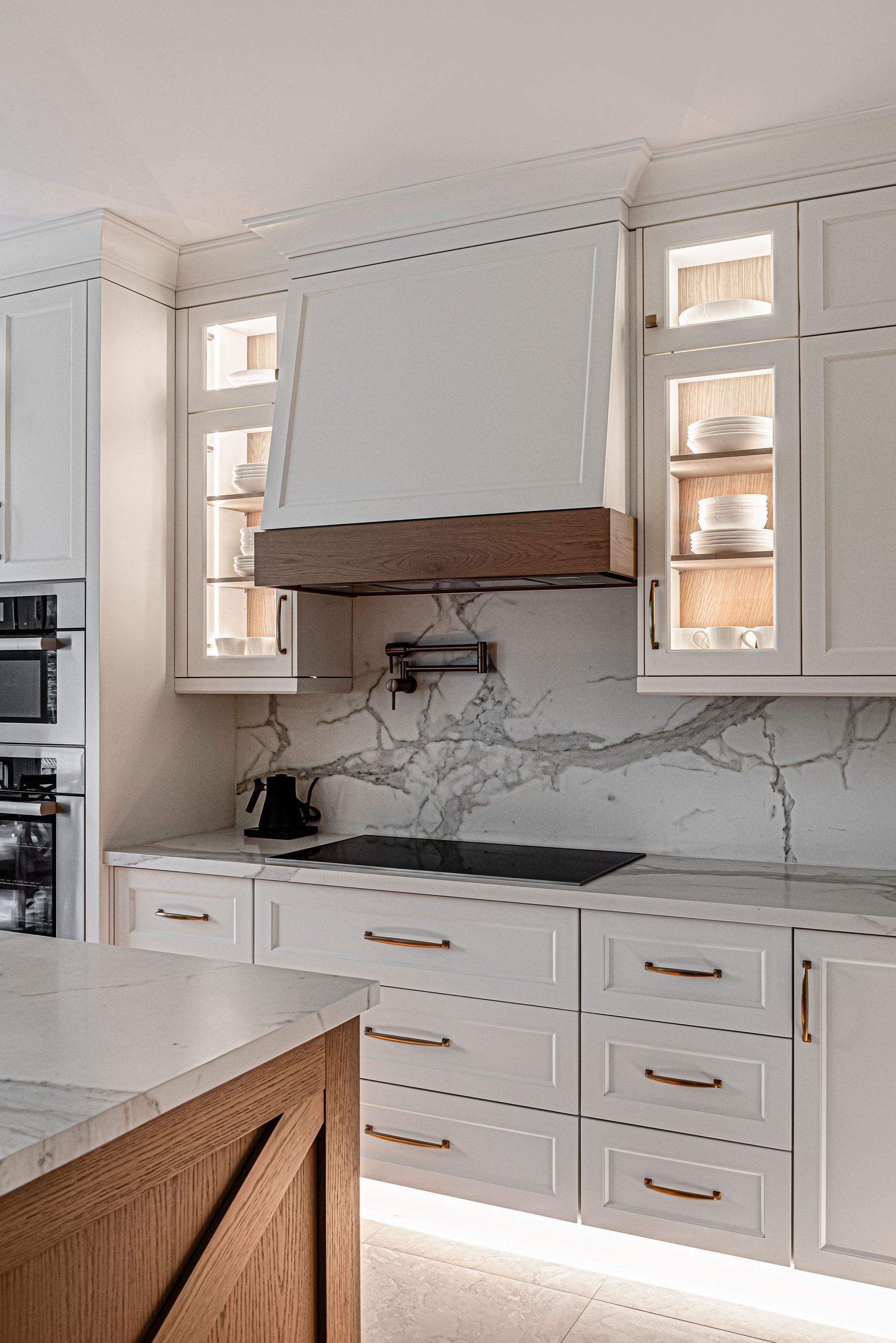 A kitchen with white cabinets and a wooden island.