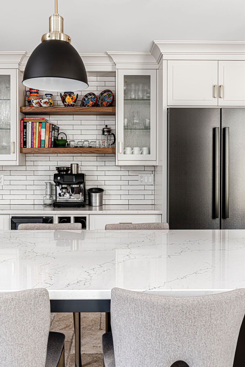 A kitchen with white cabinets , a stainless steel refrigerator , a table and chairs.