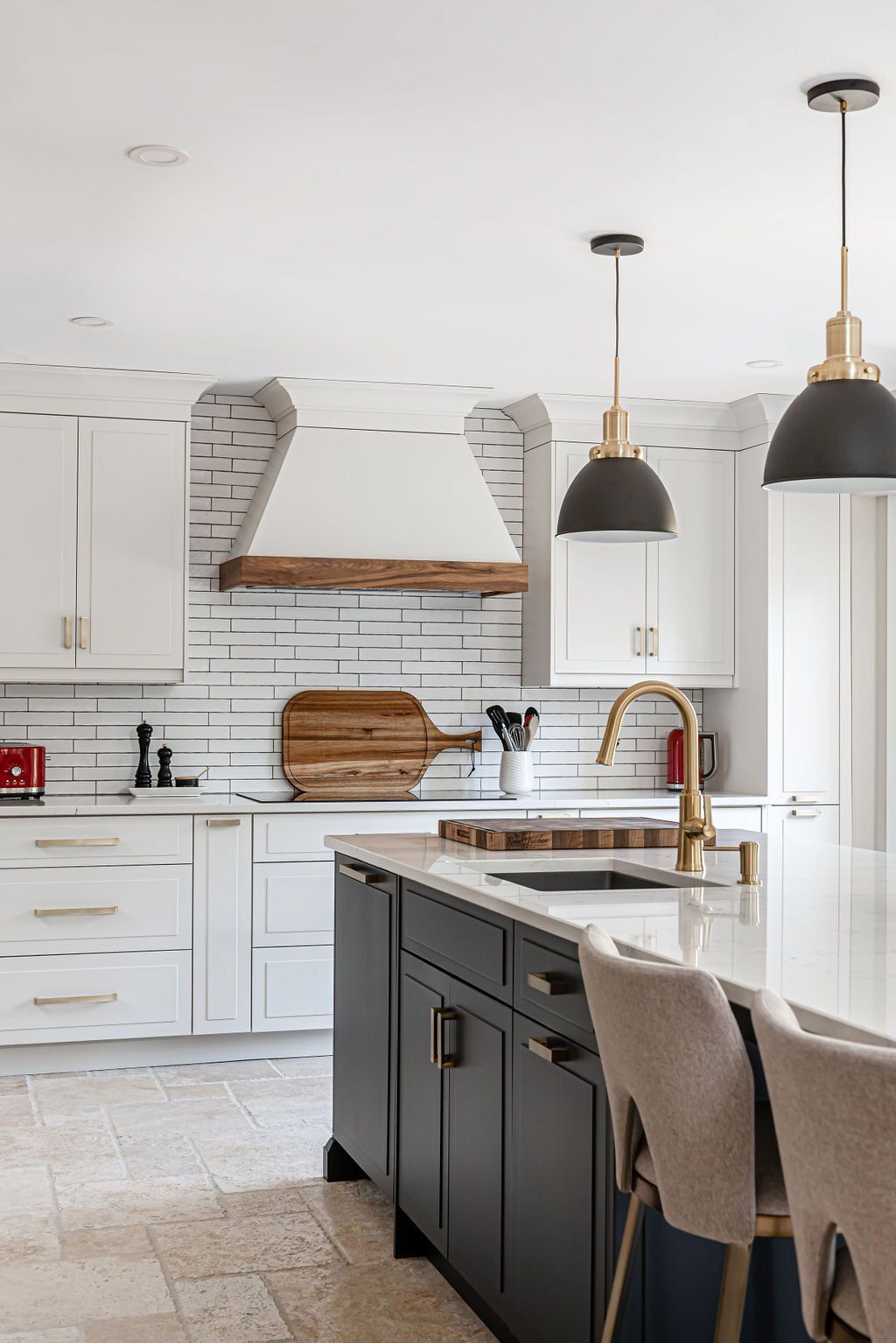 A kitchen with white cabinets , black cabinets , a large island , a sink , and a stove.
