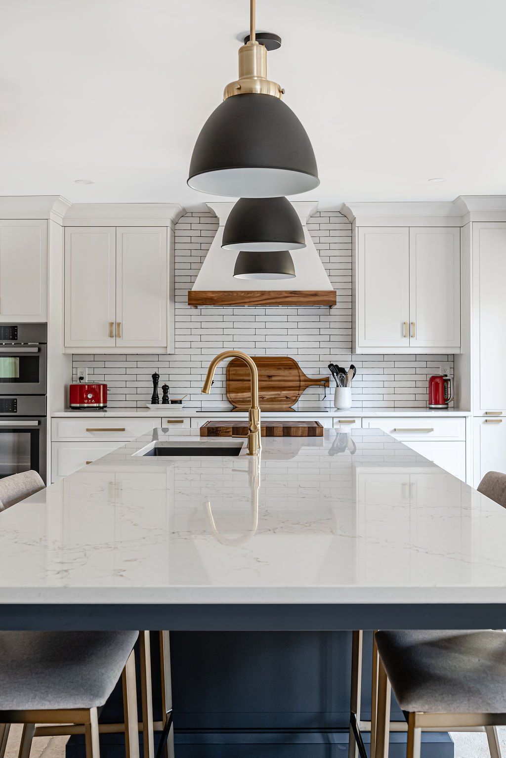 A kitchen with white cabinets , a sink , and a large island.