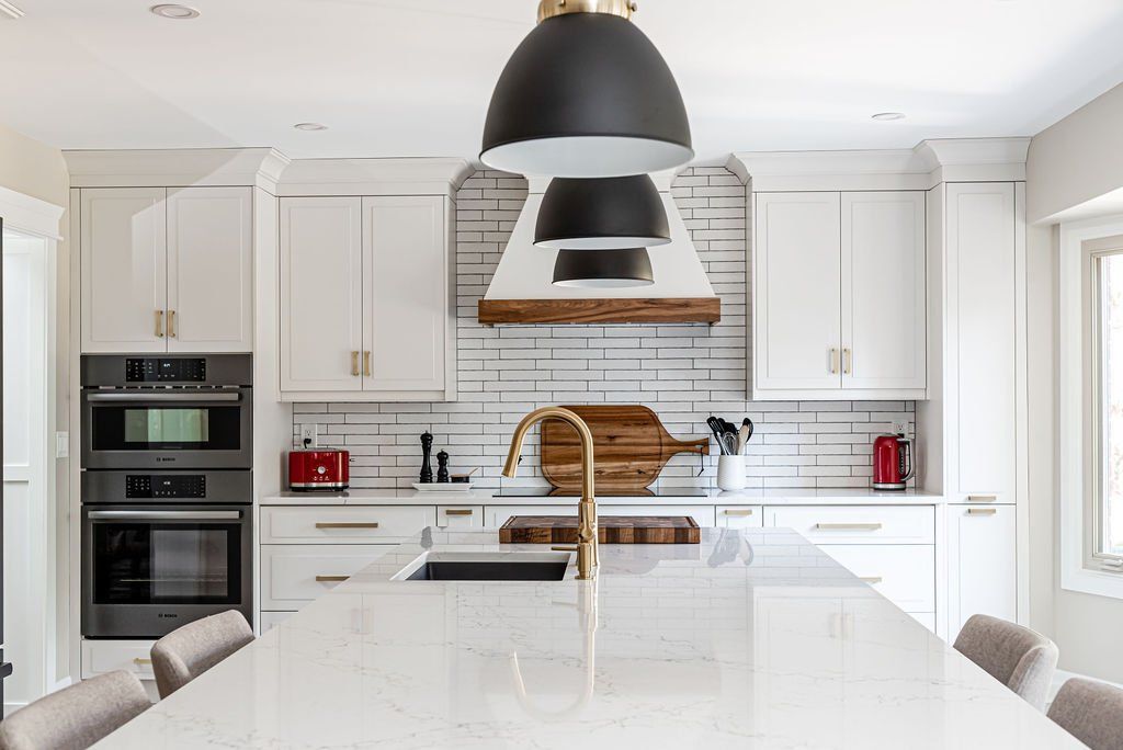 A kitchen with white cabinets , stainless steel appliances and a large island.